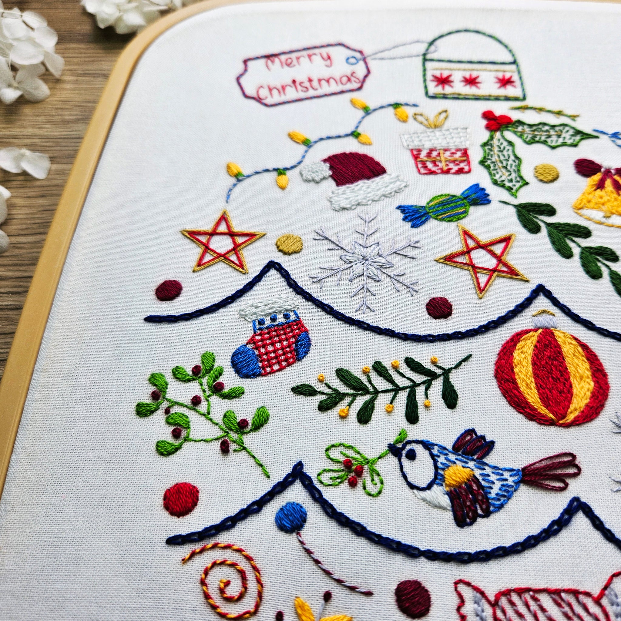 Embroidered Christmas-themed design on fabric with festive elements.