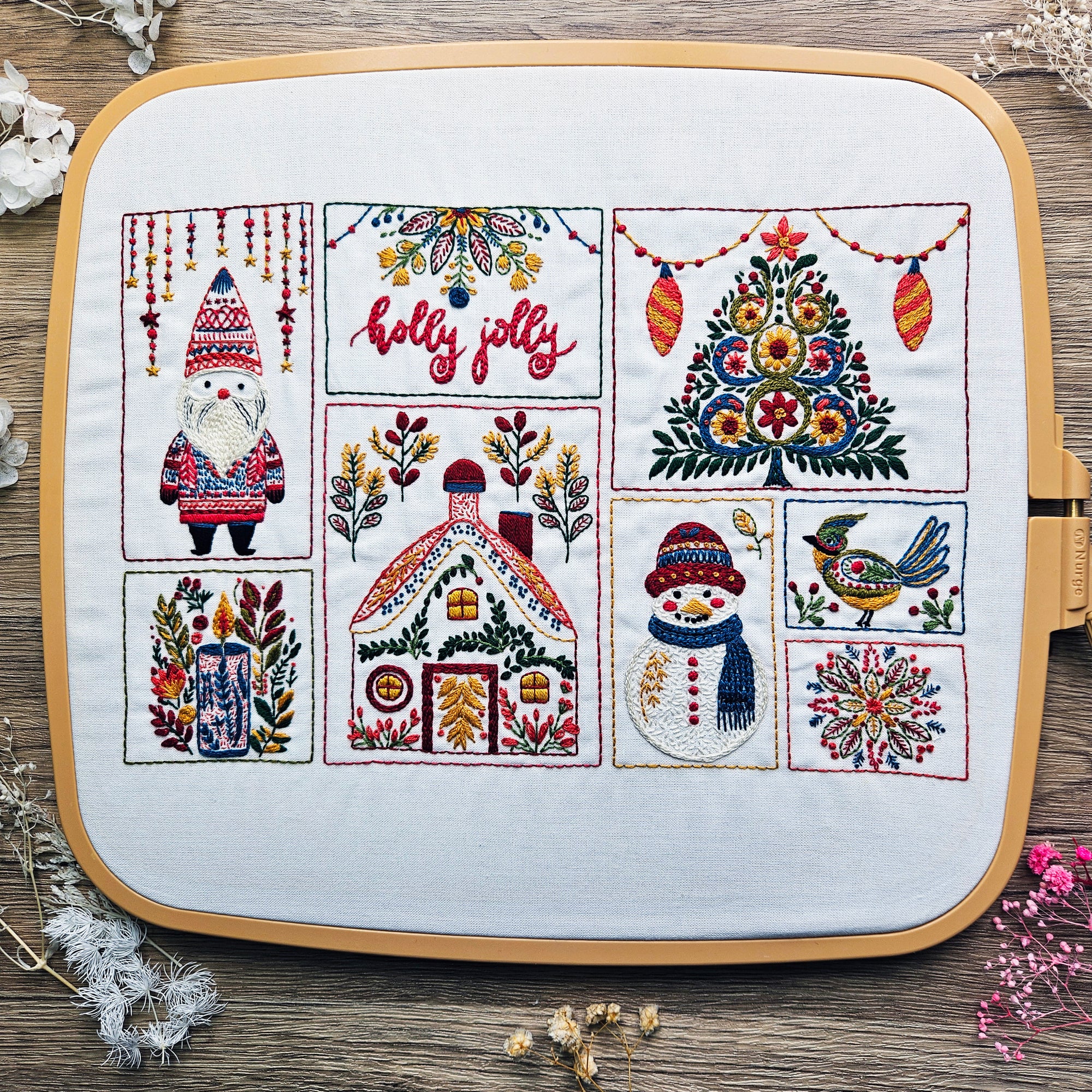 Embroidery hoop with Christmas-themed designs on a wooden surface