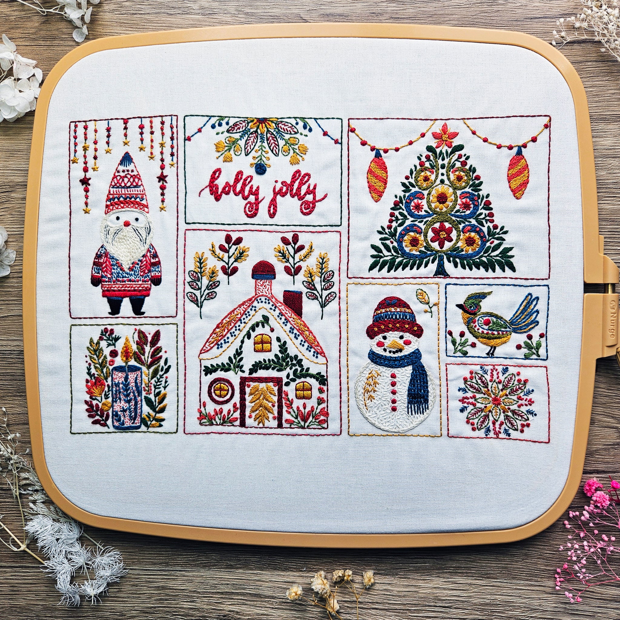 Embroidery hoop with Christmas-themed designs on a wooden surface