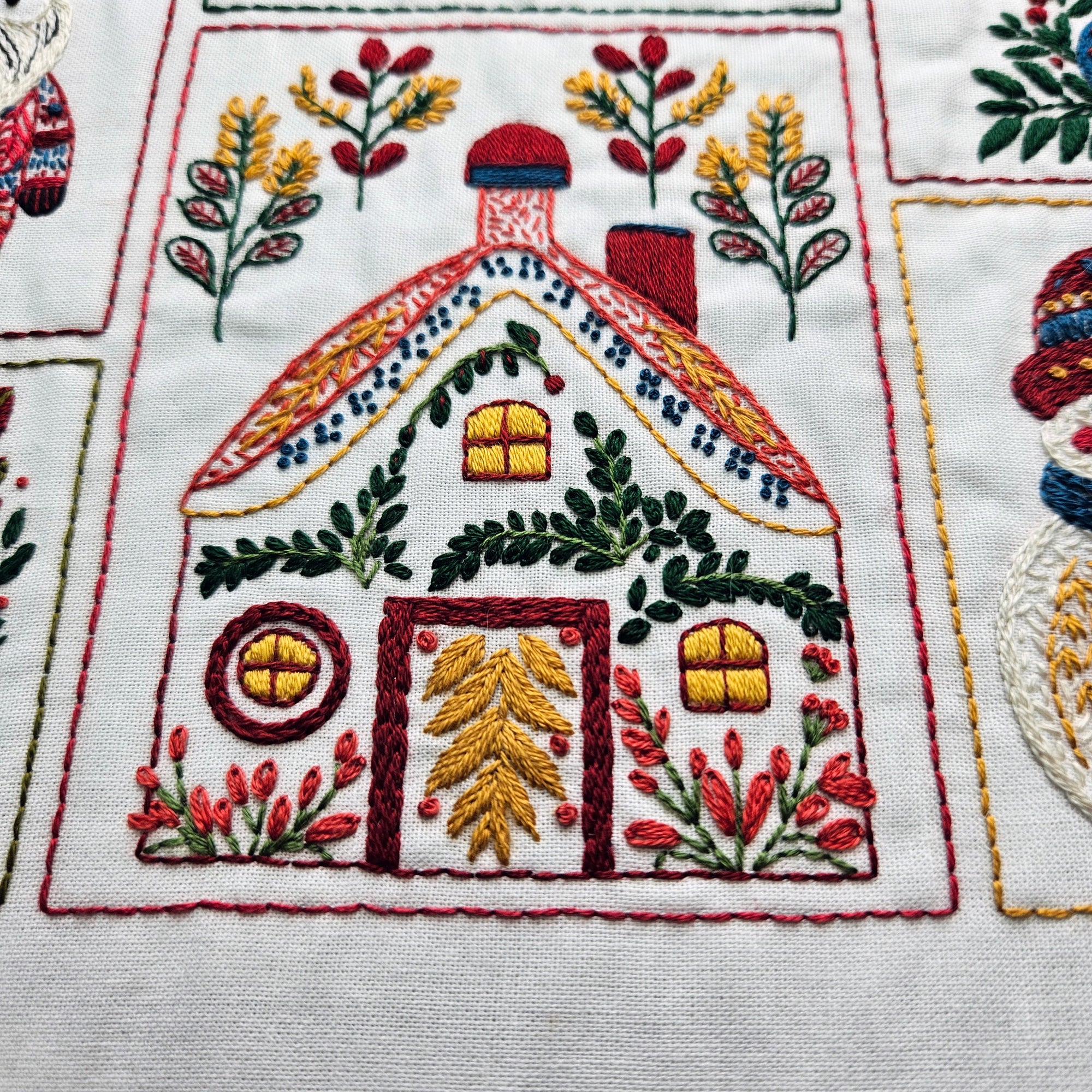 Embroidered design of a house with festive elements on fabric