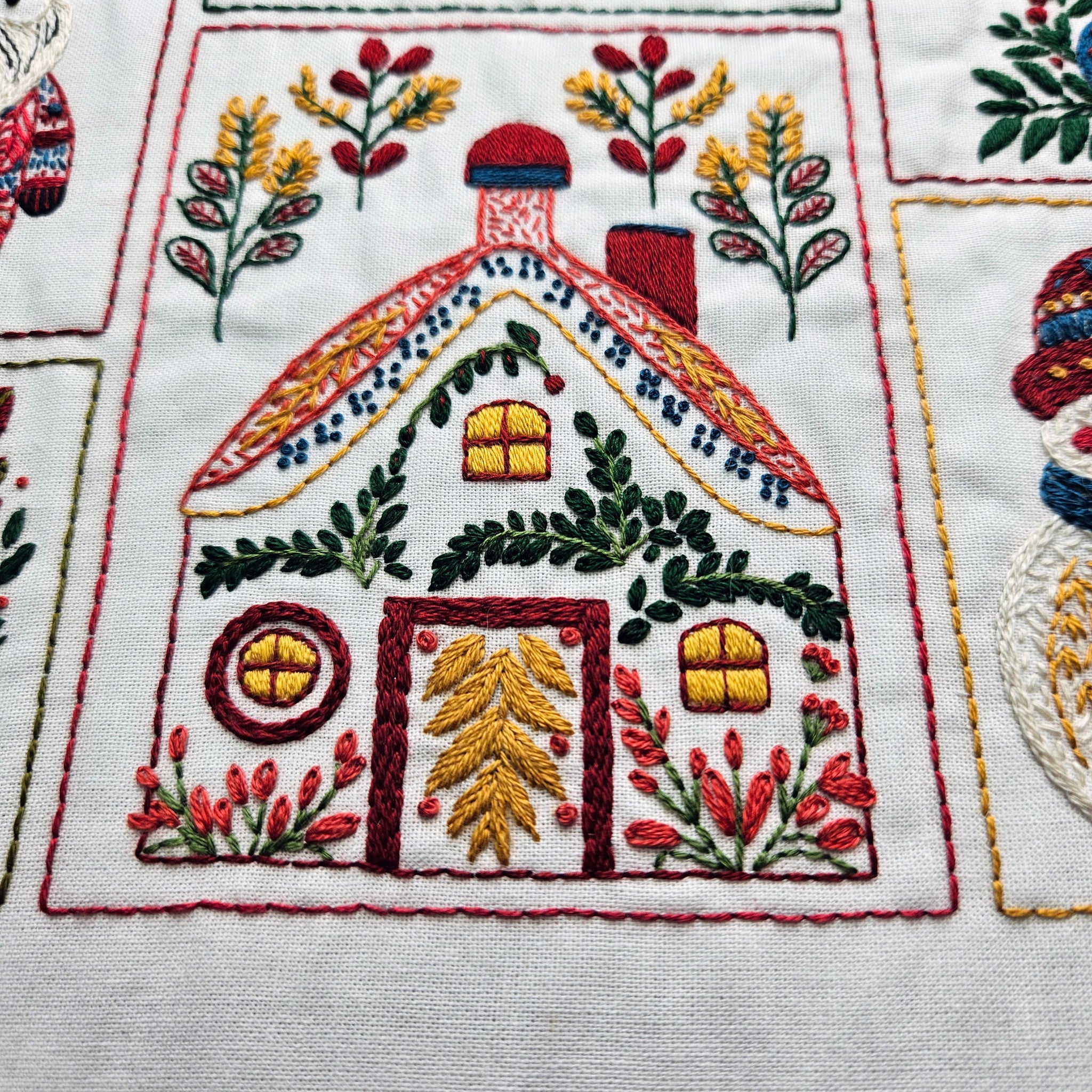 Embroidered design of a house with festive elements on fabric