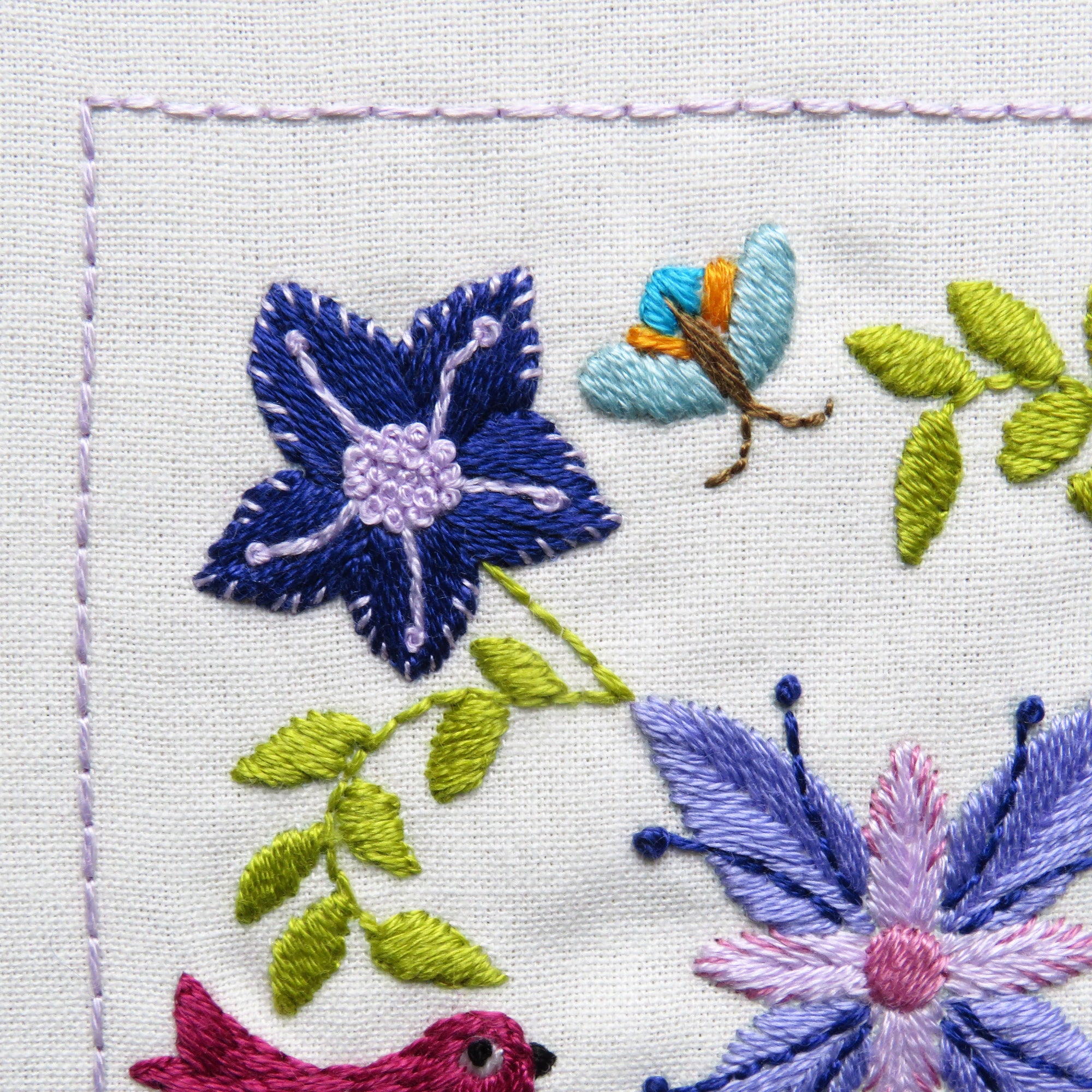 Embroidered design with flowers, leaves, and a bird on a white background