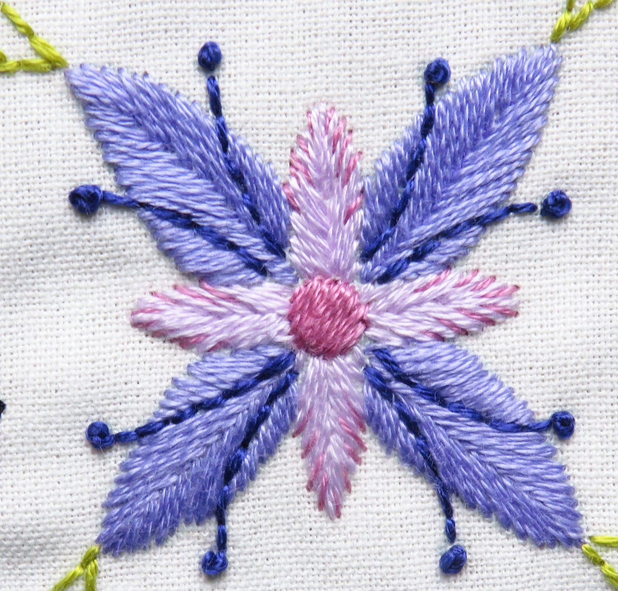 Embroidered flower design with purple and pink colors on a white background