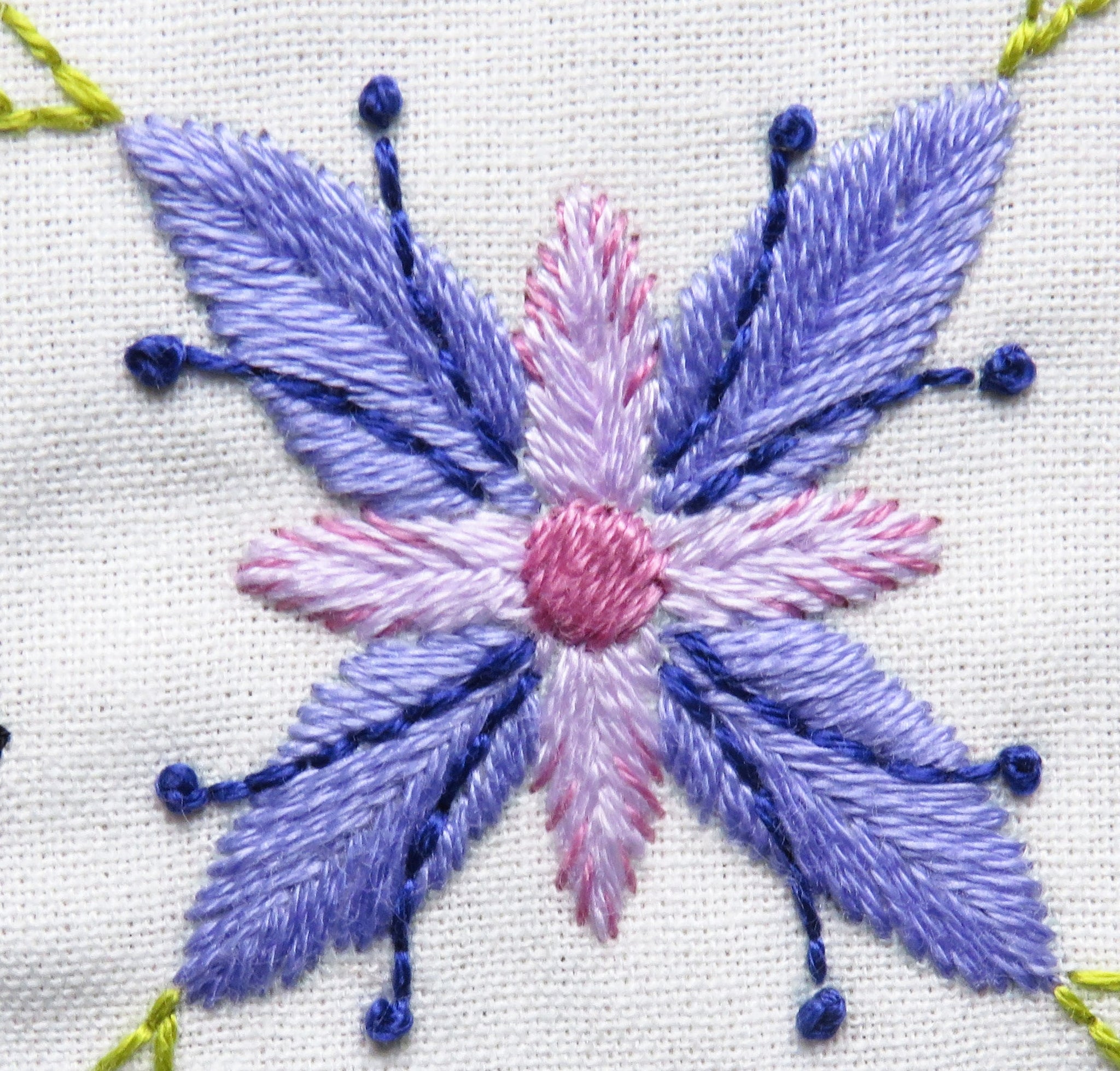 Embroidered flower design with purple and pink colors on a white background
