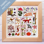 Framed fabric pattern with embroidered animals, plants, and nature-themed designs.
