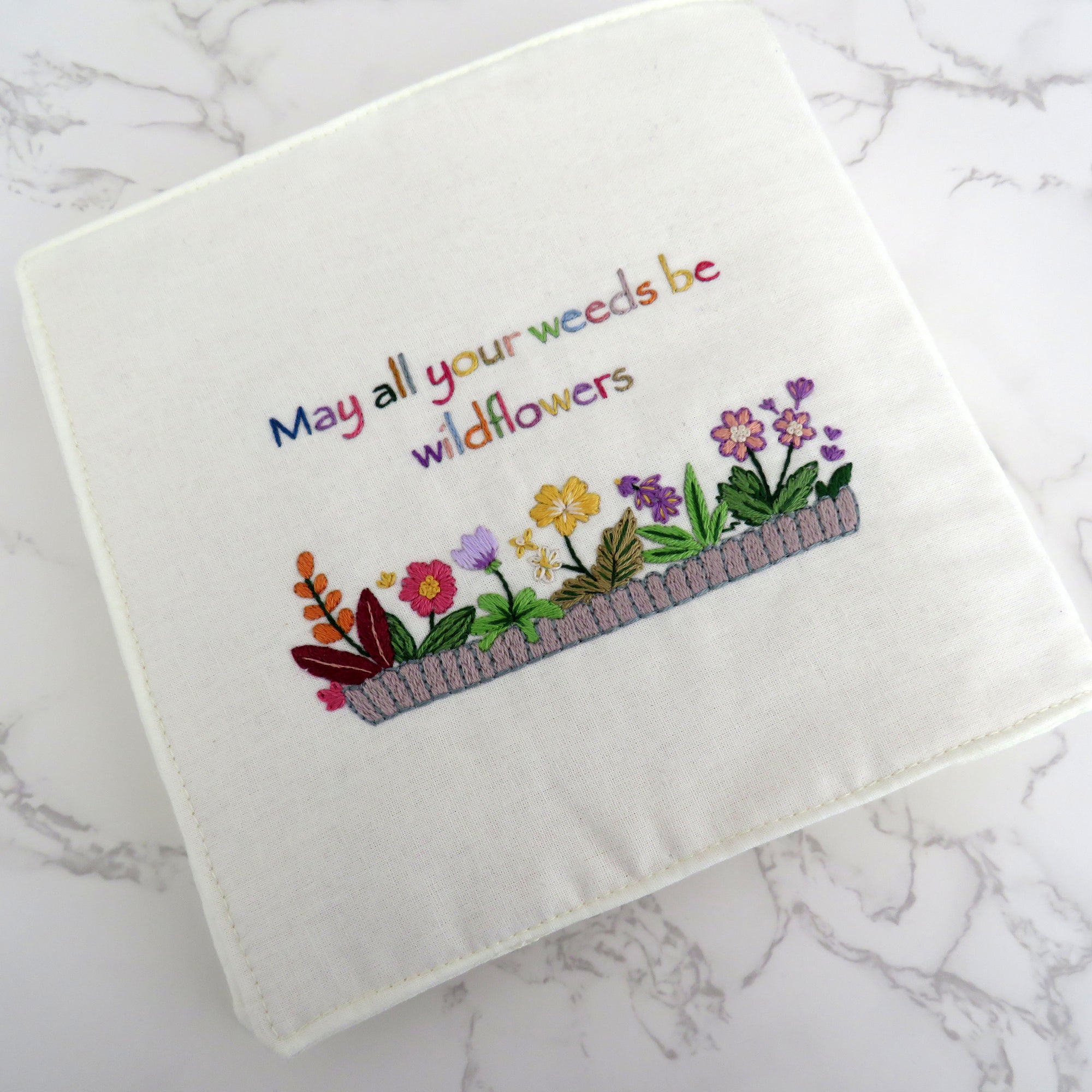 Embroidered towel with floral design and text on a marble surface