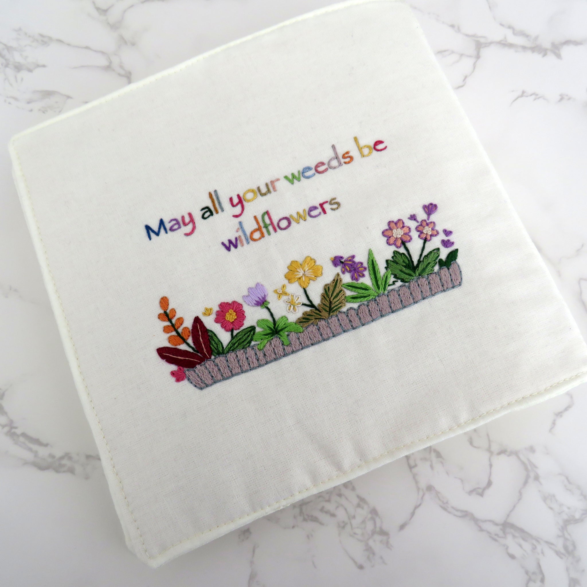 Embroidered towel with floral design and text on a marble surface
