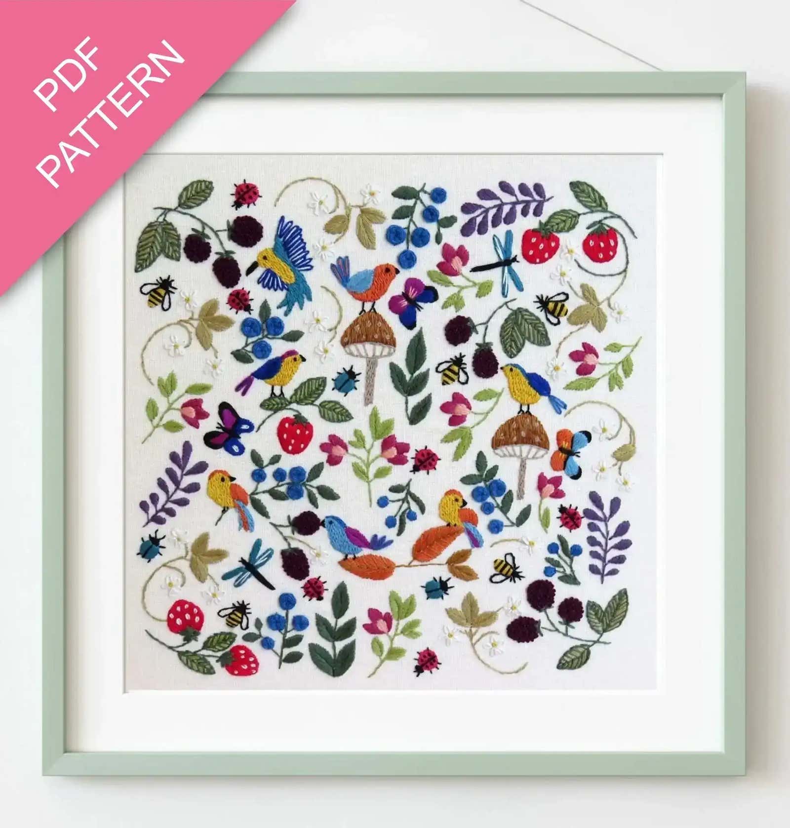 Embroidery pattern with colorful birds and flowers in a green frame.