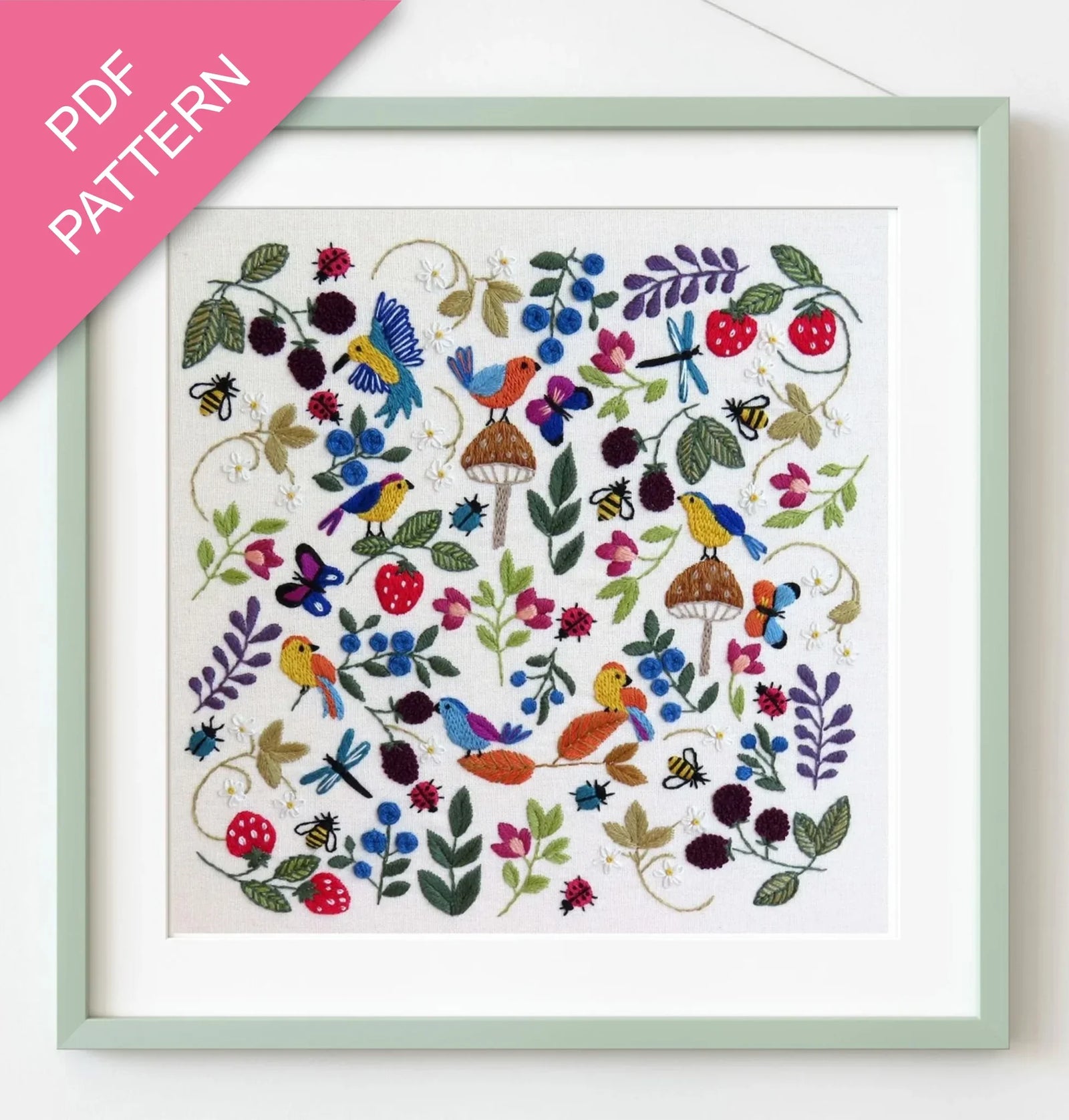 Embroidery pattern with colorful birds and flowers in a green frame.