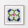 Embroidered square with a pink bird and floral patterns in a purple frame on a white background