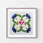 Embroidered square with a pink bird and floral patterns in a purple frame on a white background