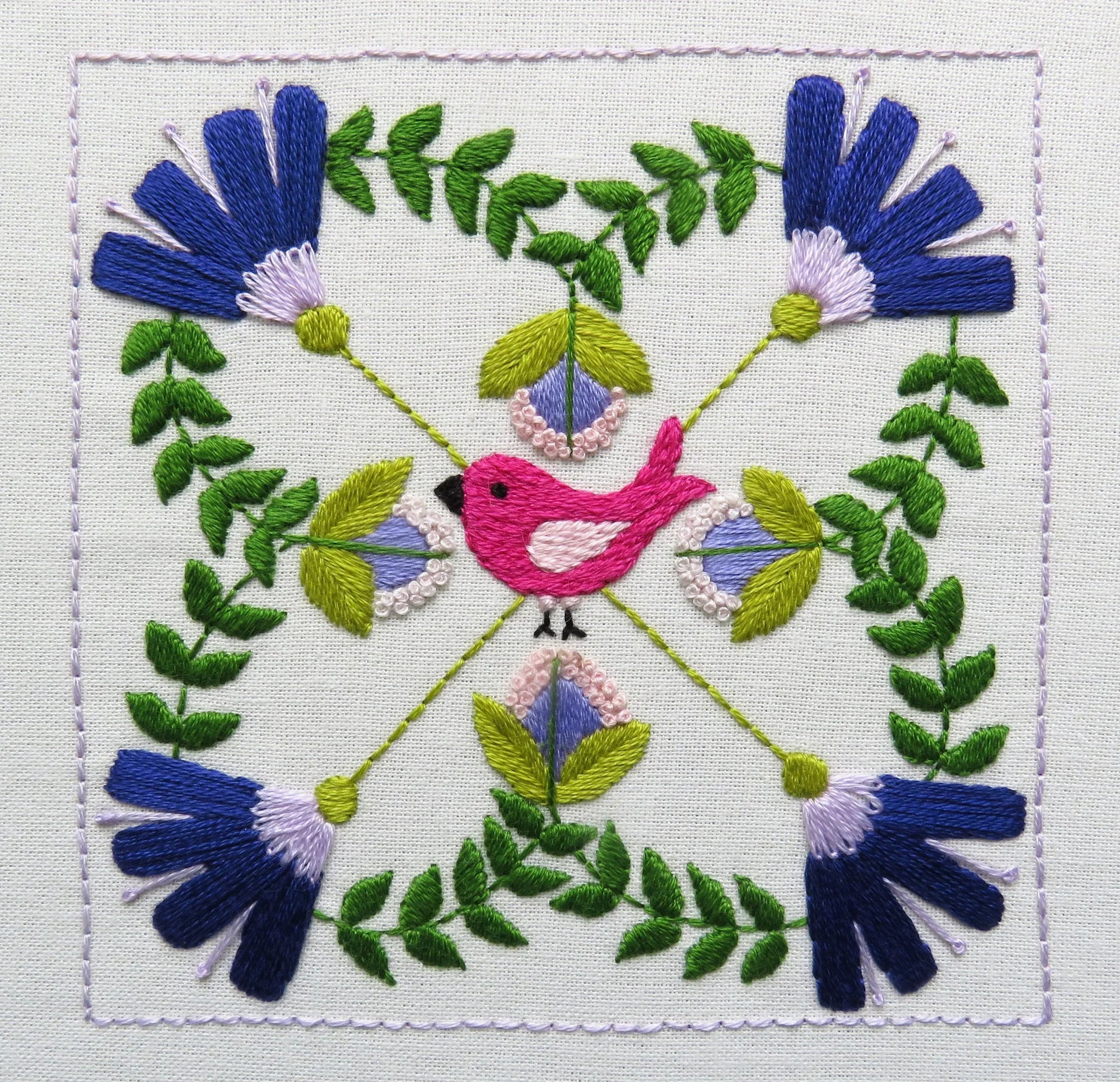 Embroidered design with a pink bird and blue flowers on a white background