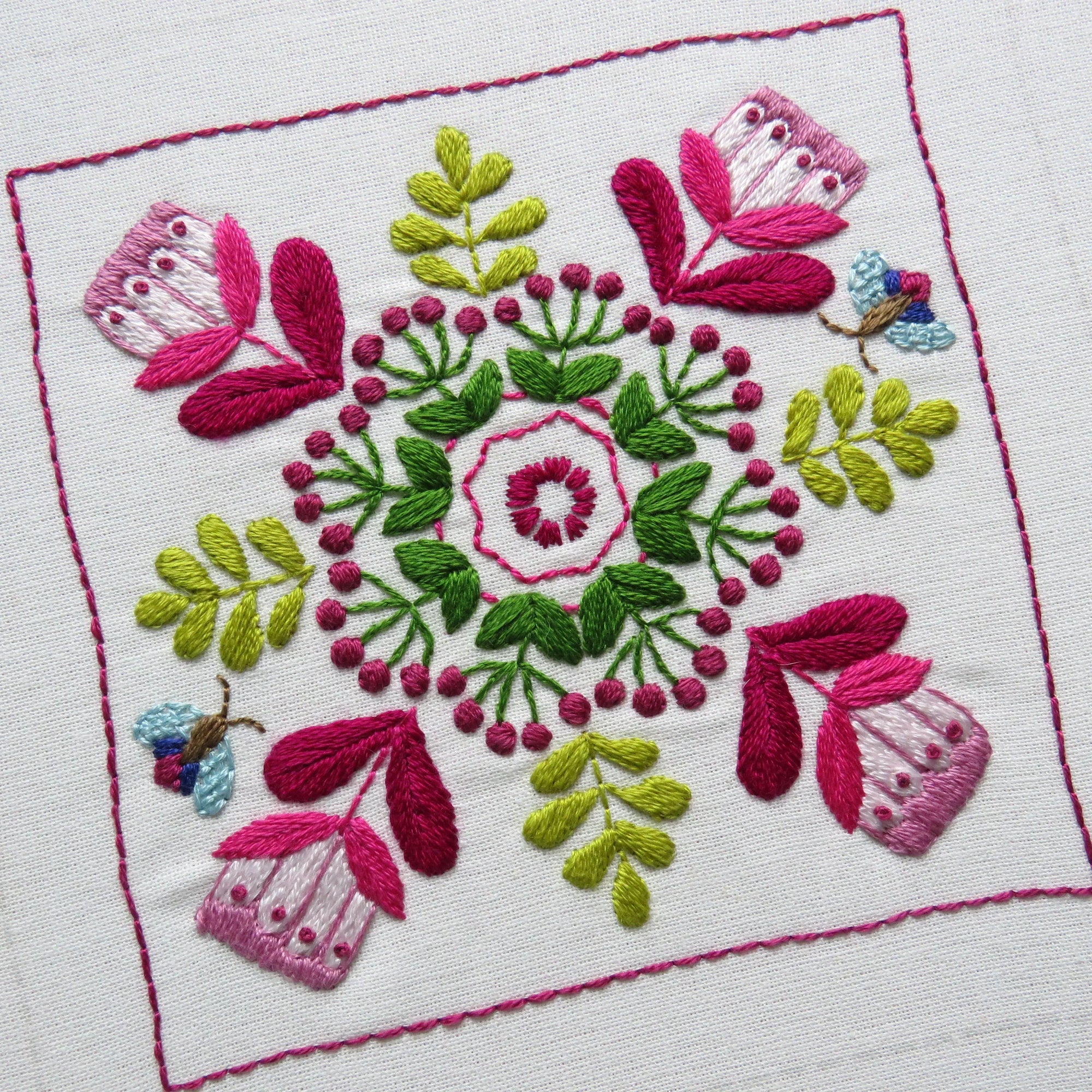 Embroidered design with pink and green flowers on a white background