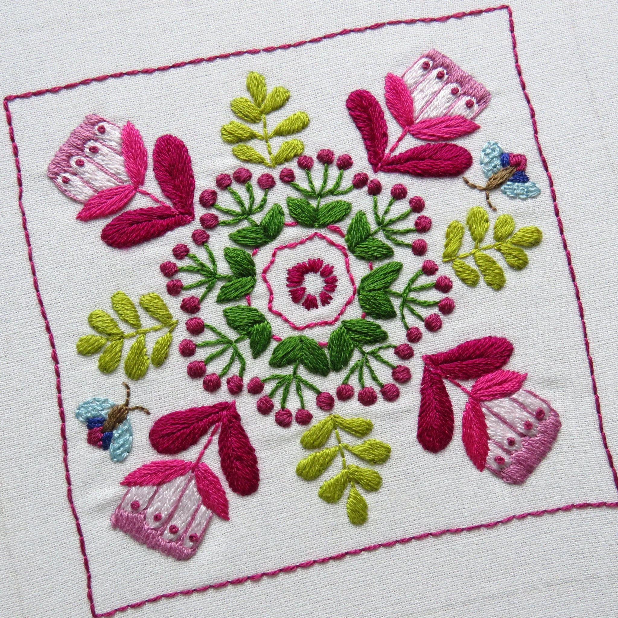 Embroidered design with pink and green flowers on a white background