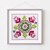Framed embroidered artwork with floral design on a white background
