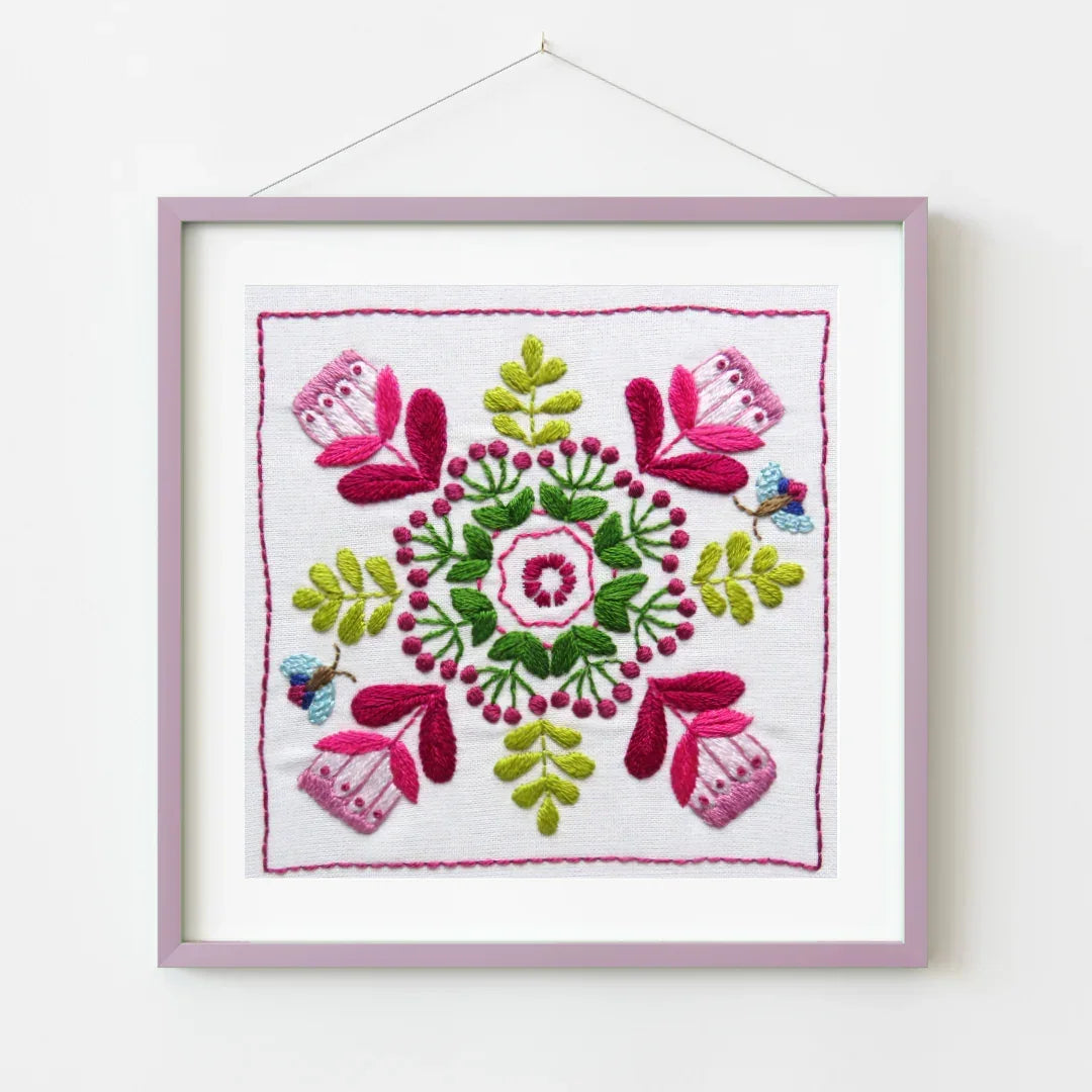 Framed embroidered artwork with floral design on a white background