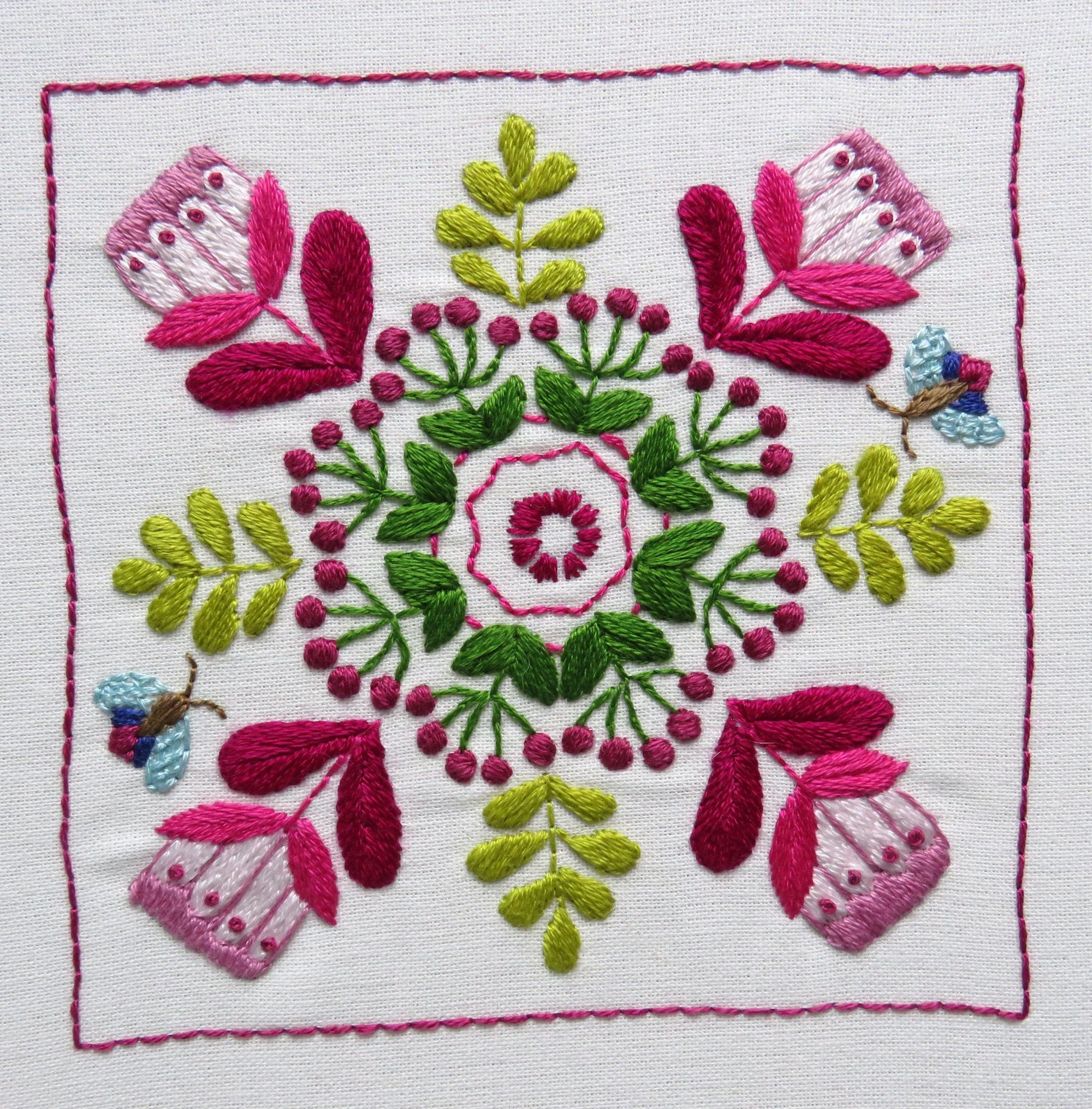 Embroidered design with pink and green flowers on a white background