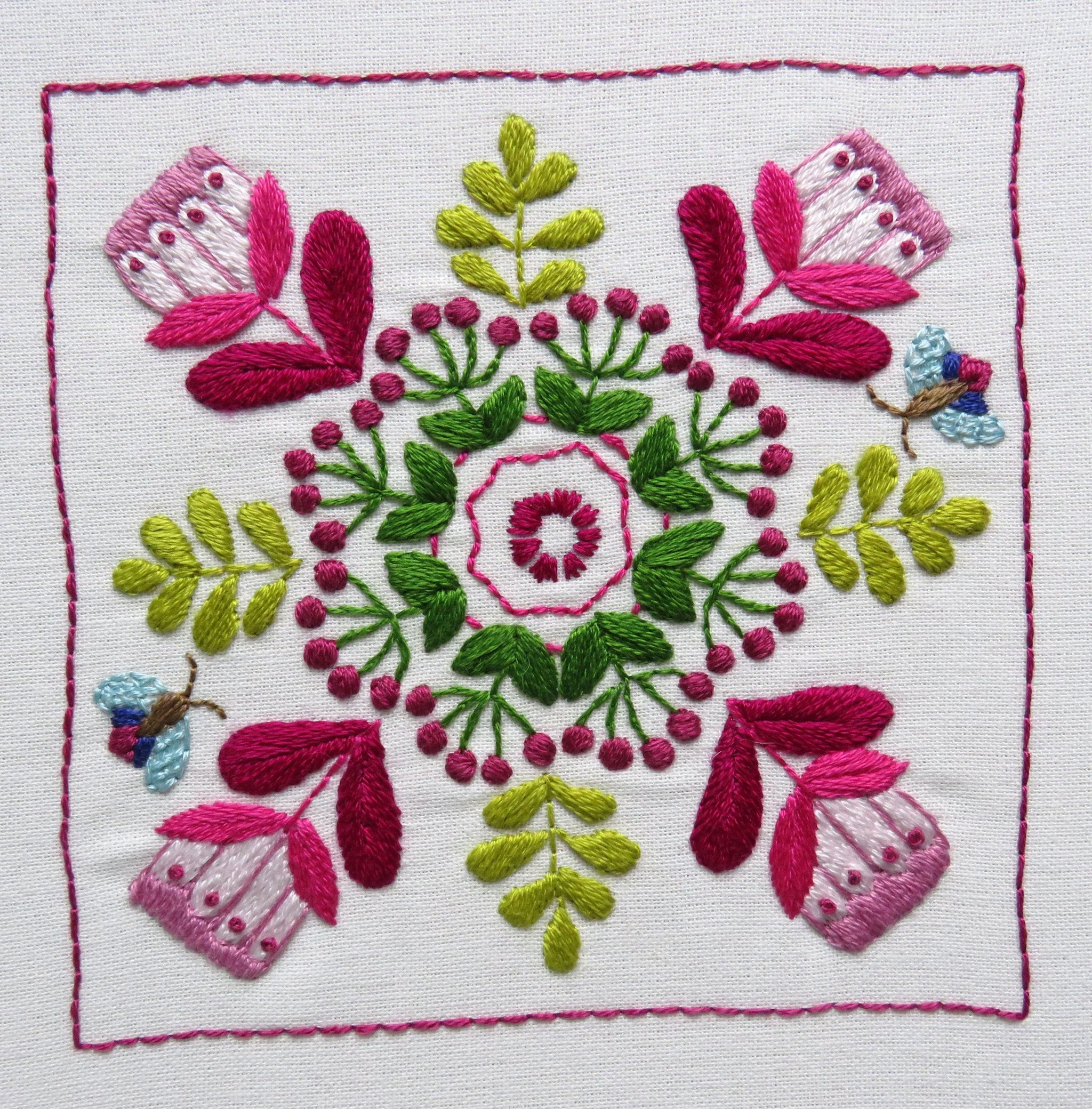 Embroidered design with pink and green flowers on a white background