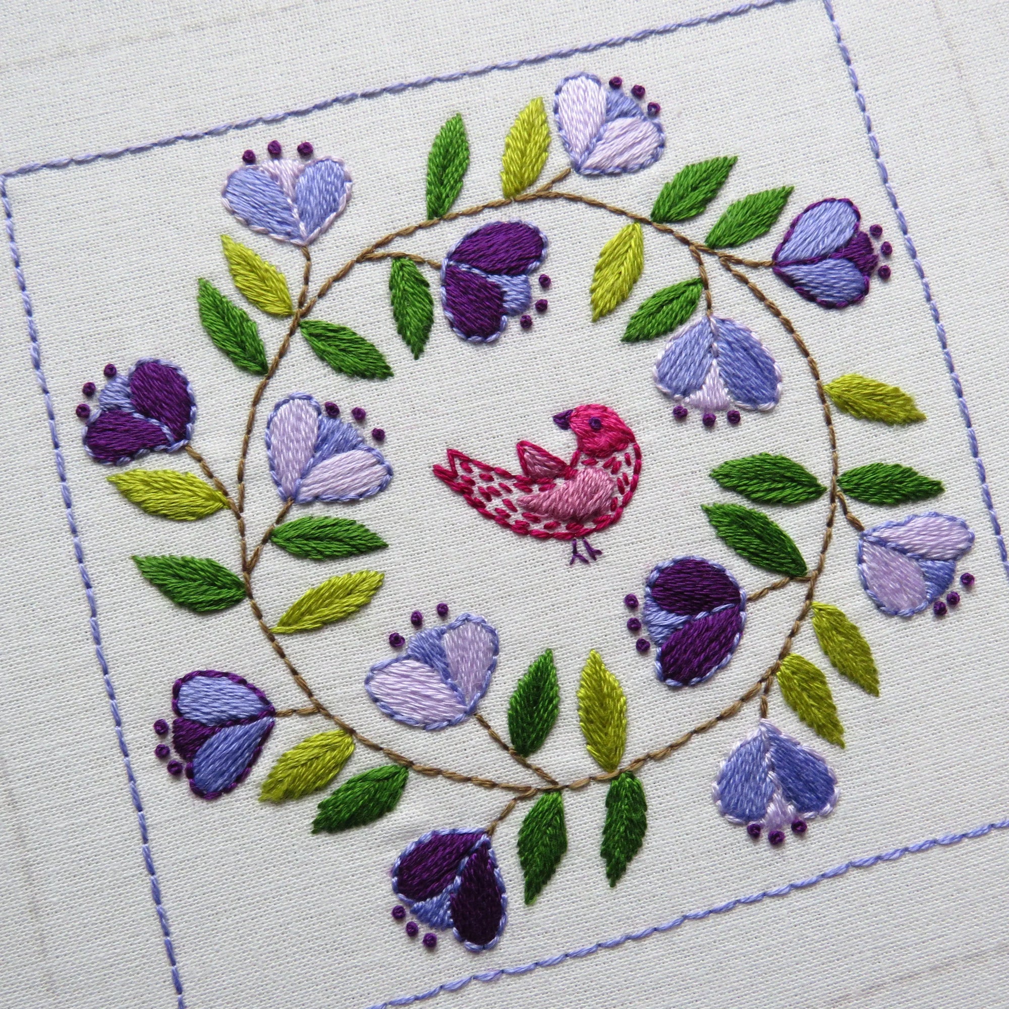 Embroidered design with a bird and flowers on white fabric