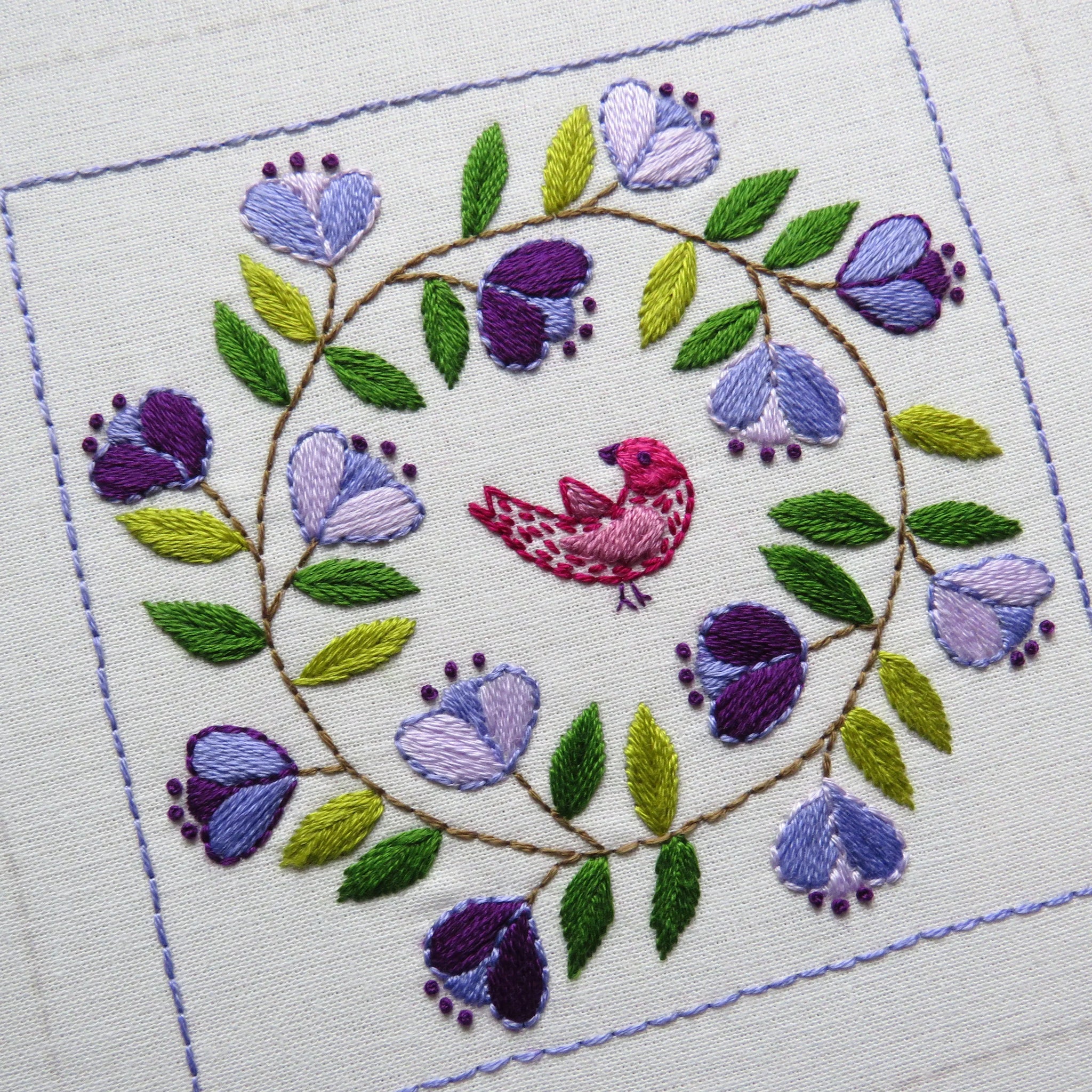 Embroidered design with a bird and flowers on white fabric