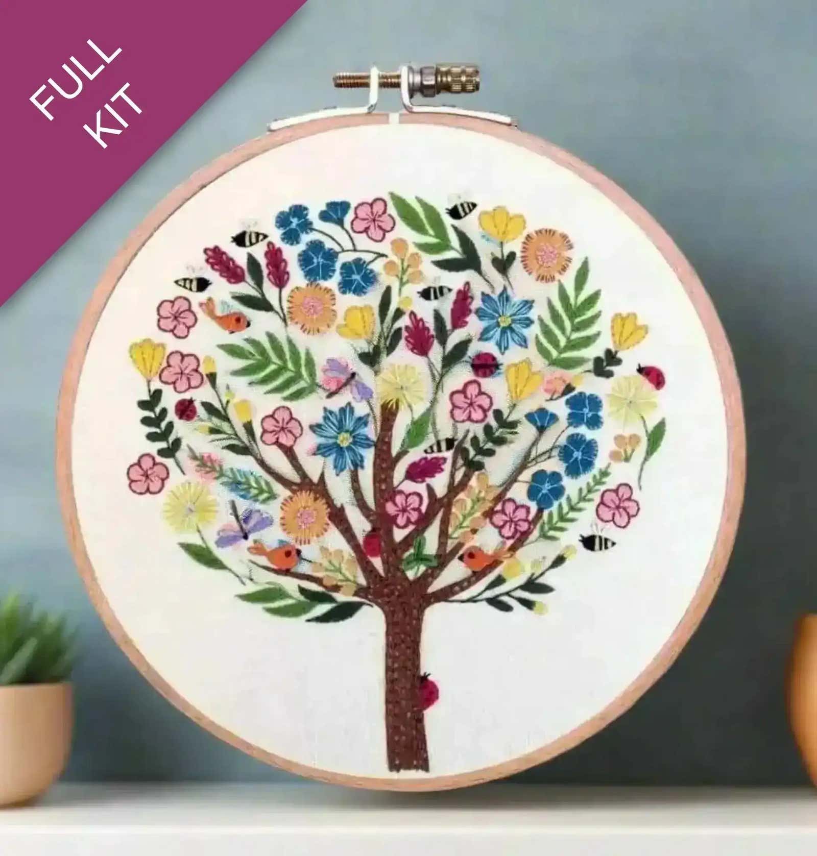 Embroidery hoop with a colorful tree design on a gradient background