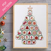 Framed cross-stitch pattern in the shape of a Christmas tree on a wooden surface with decorative items.