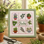 Embroidery of herbs in a green frame on a wooden surface with plants and scissors.