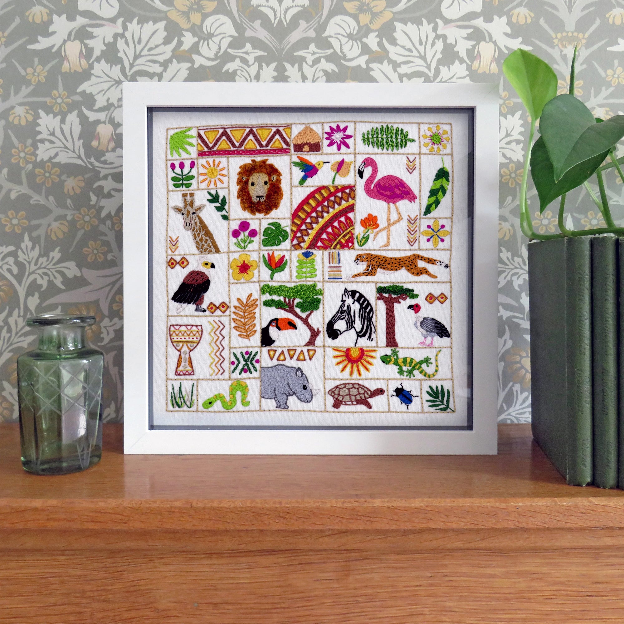 Framed artwork with colorful animal illustrations on a wooden surface with decorative background