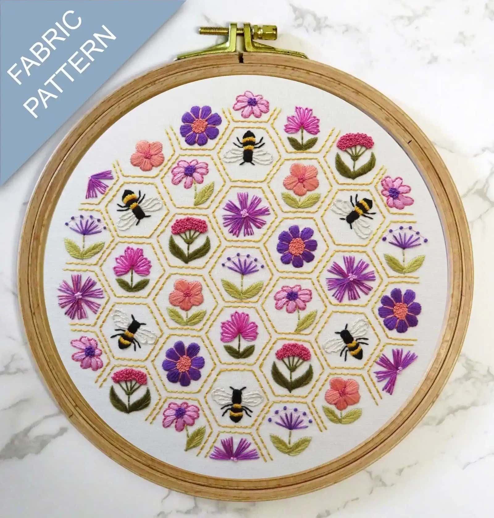 Embroidery hoop with floral and bee pattern on a marble surface