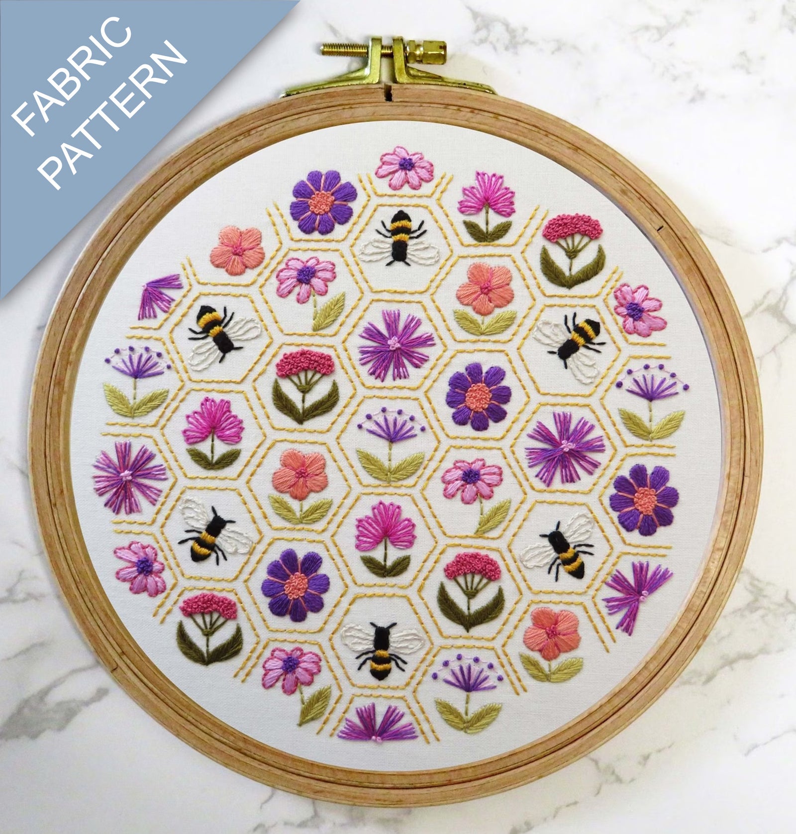 Embroidery hoop with floral and bee pattern on a marble surface