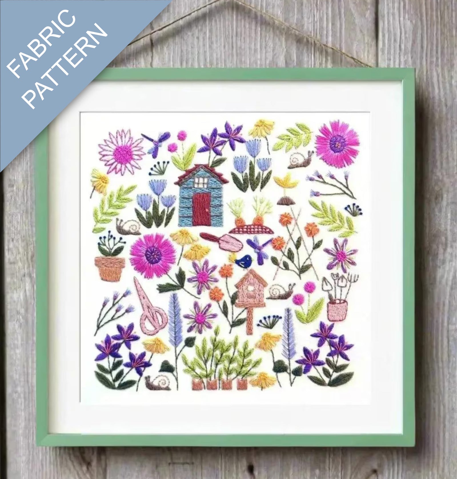 Framed fabric pattern with colorful flowers and birdhouses on a wooden surface