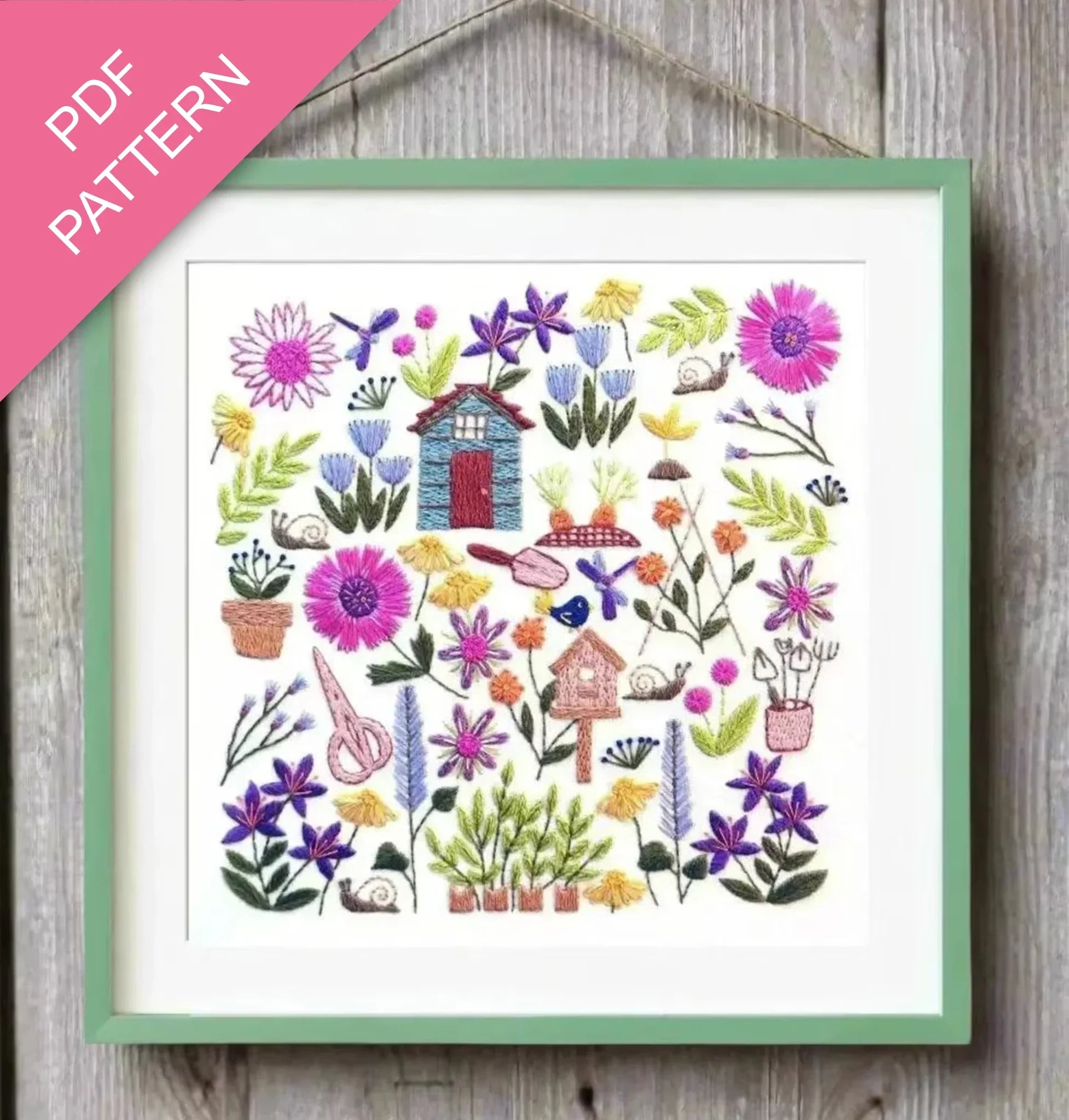 Embroidery pattern with flowers and small houses on a wooden surface, labeled 'PDF Pattern'.