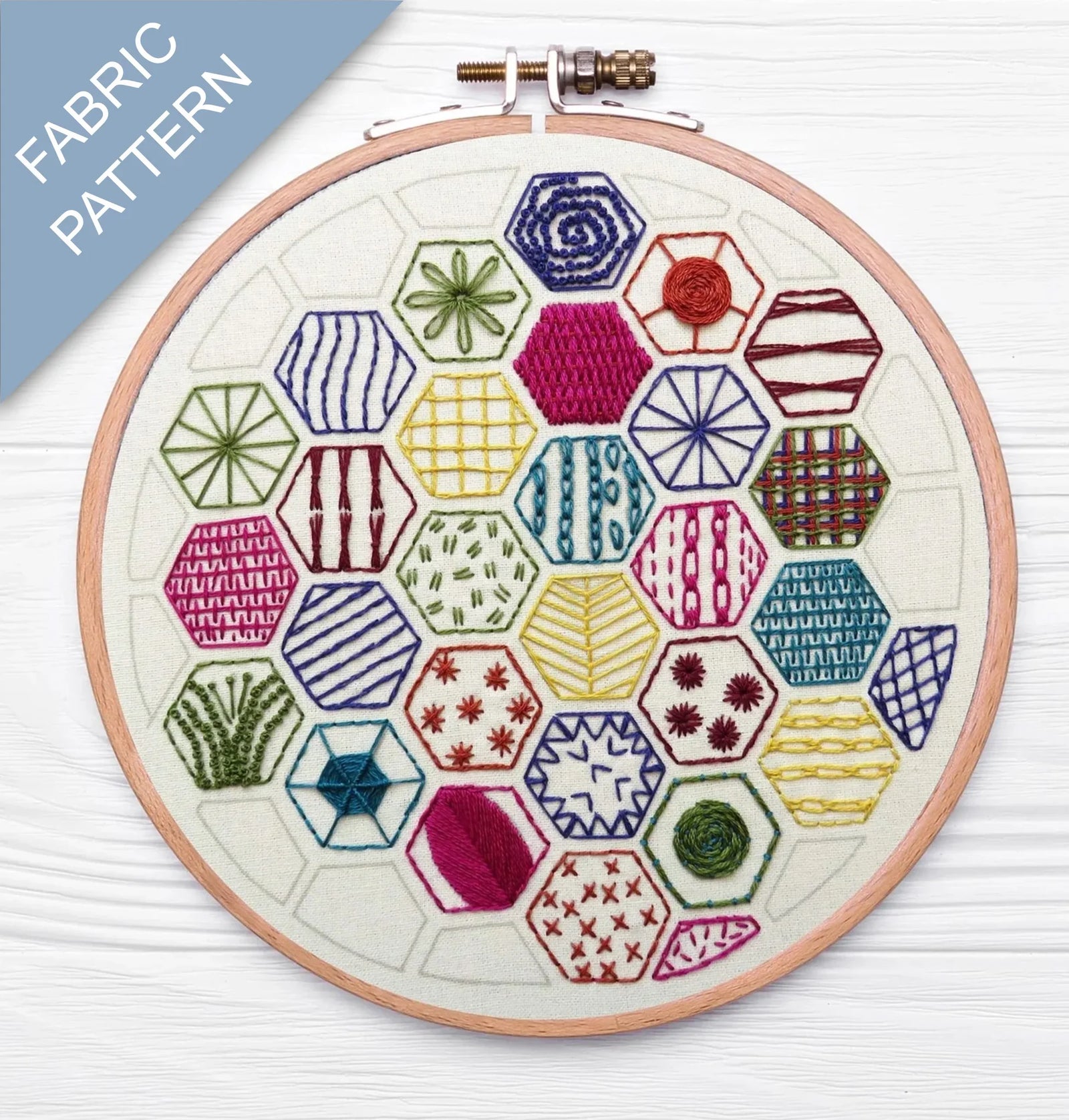 Embroidery hoop with colorful geometric pattern on a white background