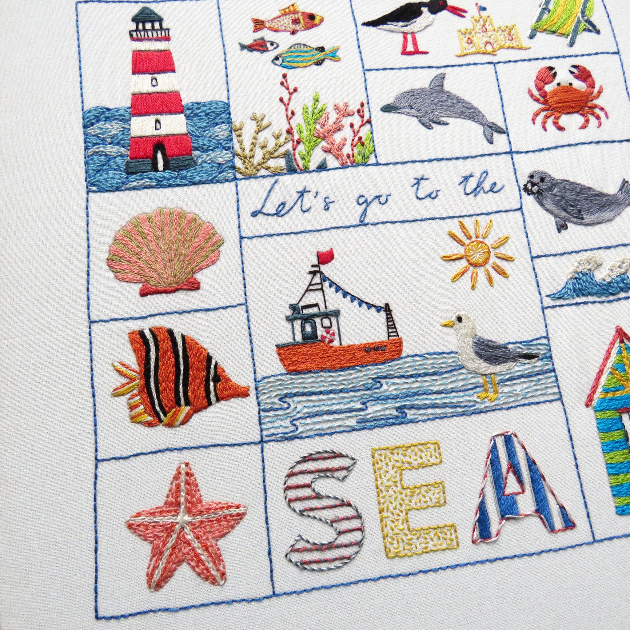 Embroidered panel with sea-themed designs including a lighthouse, fish, and seagull.