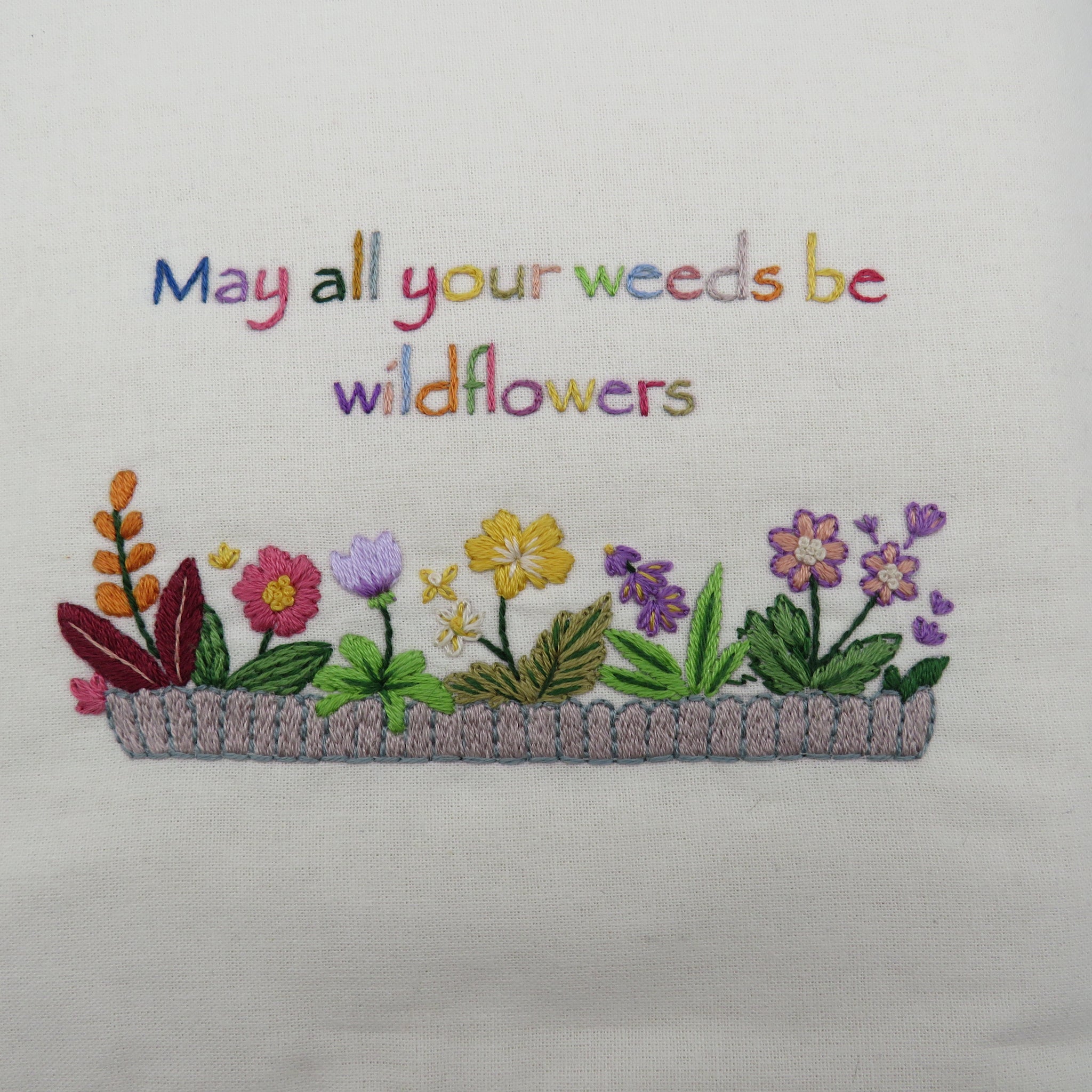 Embroidery of flowers with colorful text on a light background