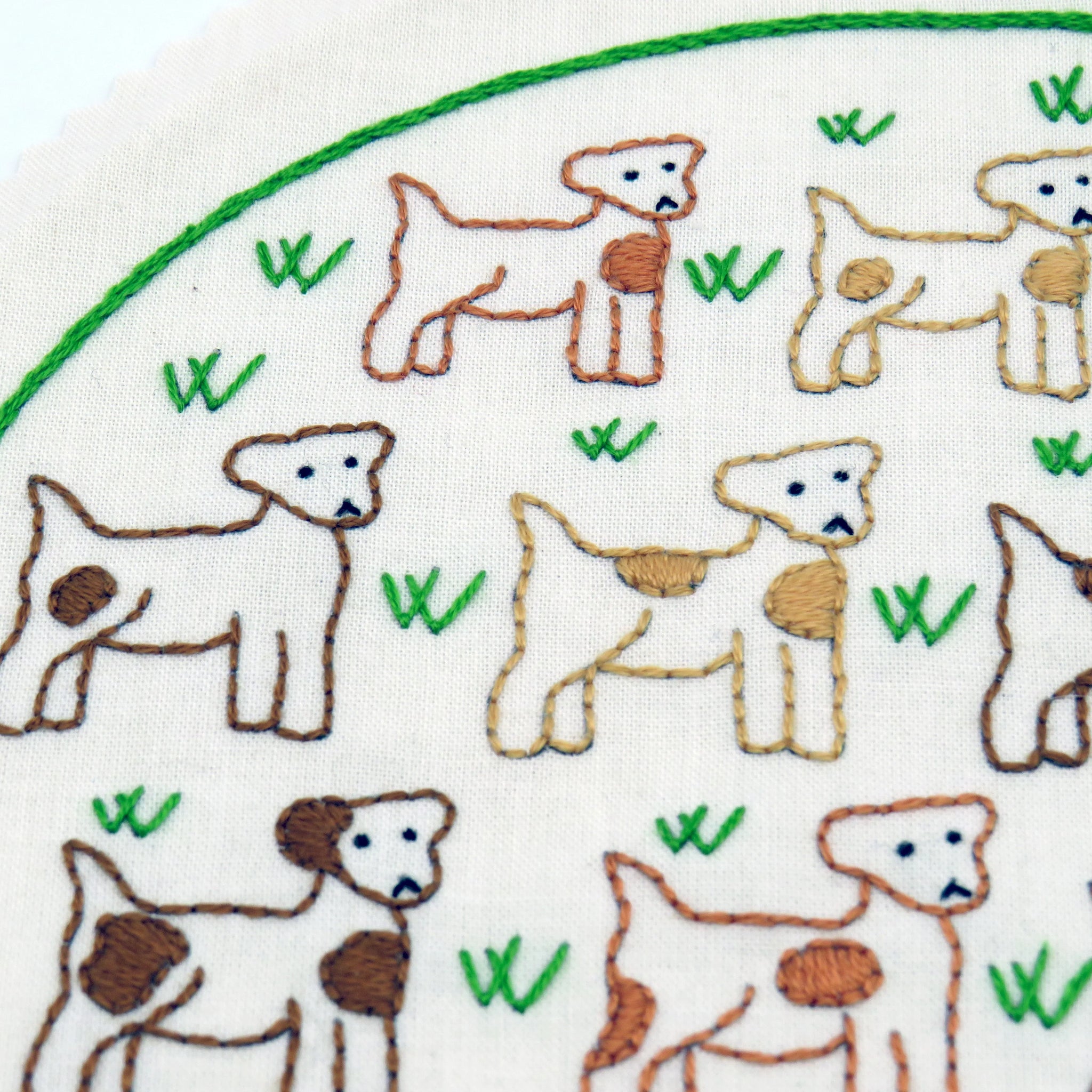 Embroidered pattern of dogs on fabric with green leaves.