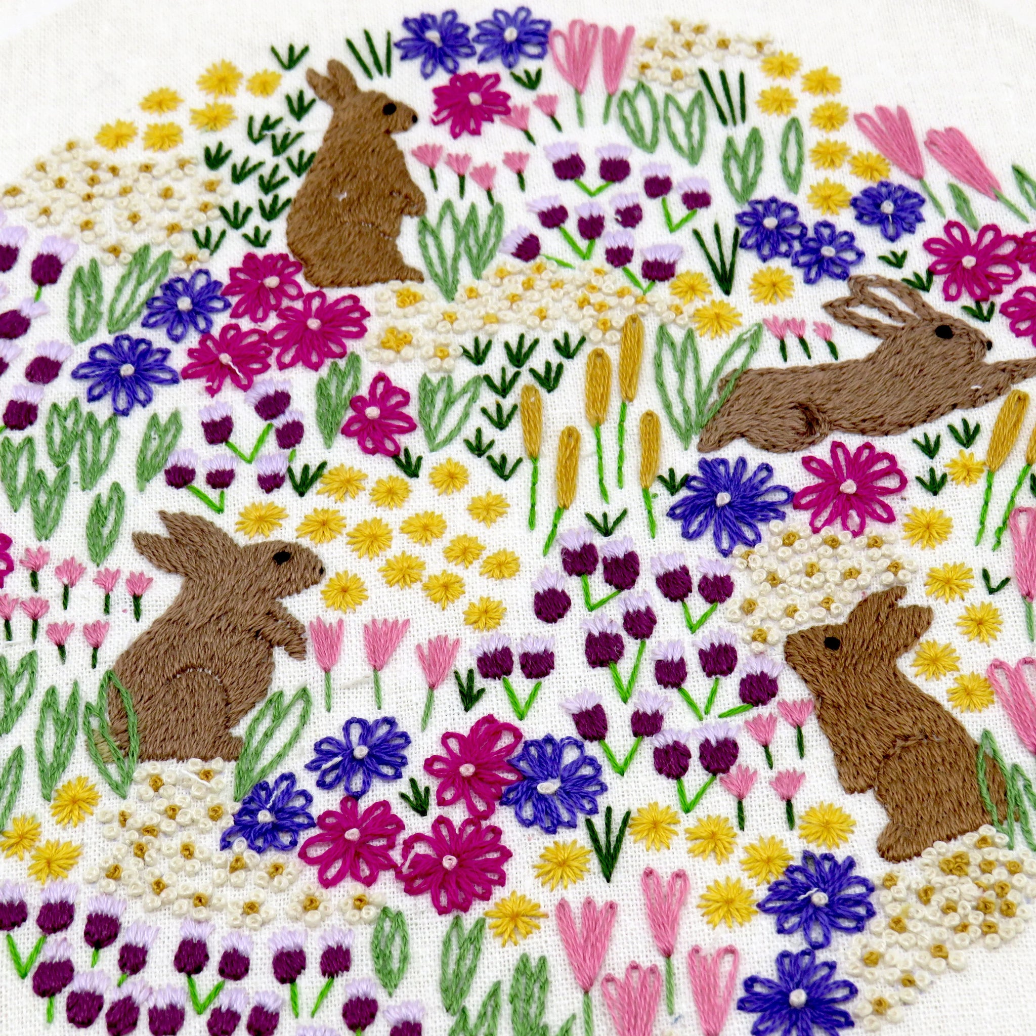 Embroidered design of rabbits and flowers on a white background
