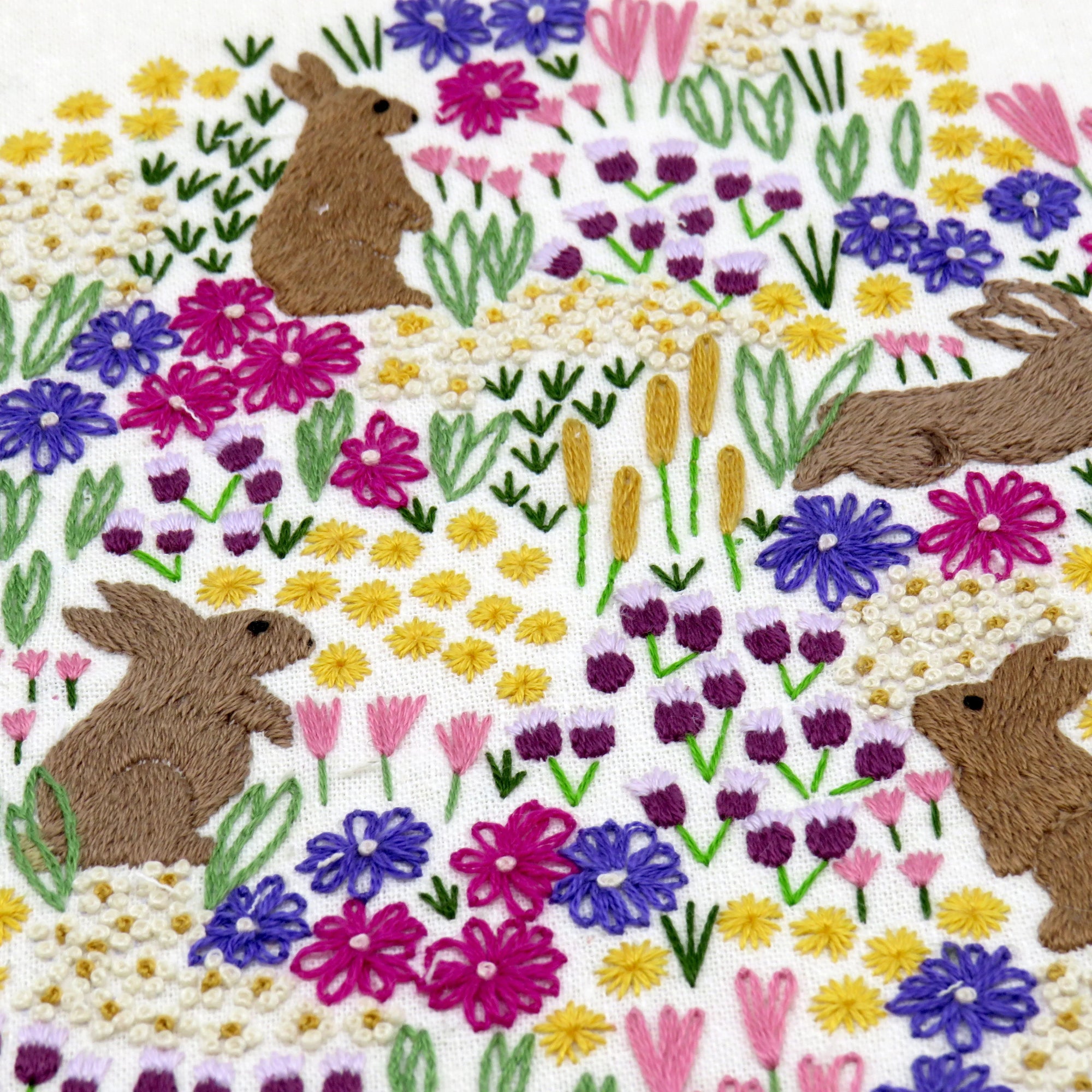 Embroidered design of bunnies and flowers on a white background