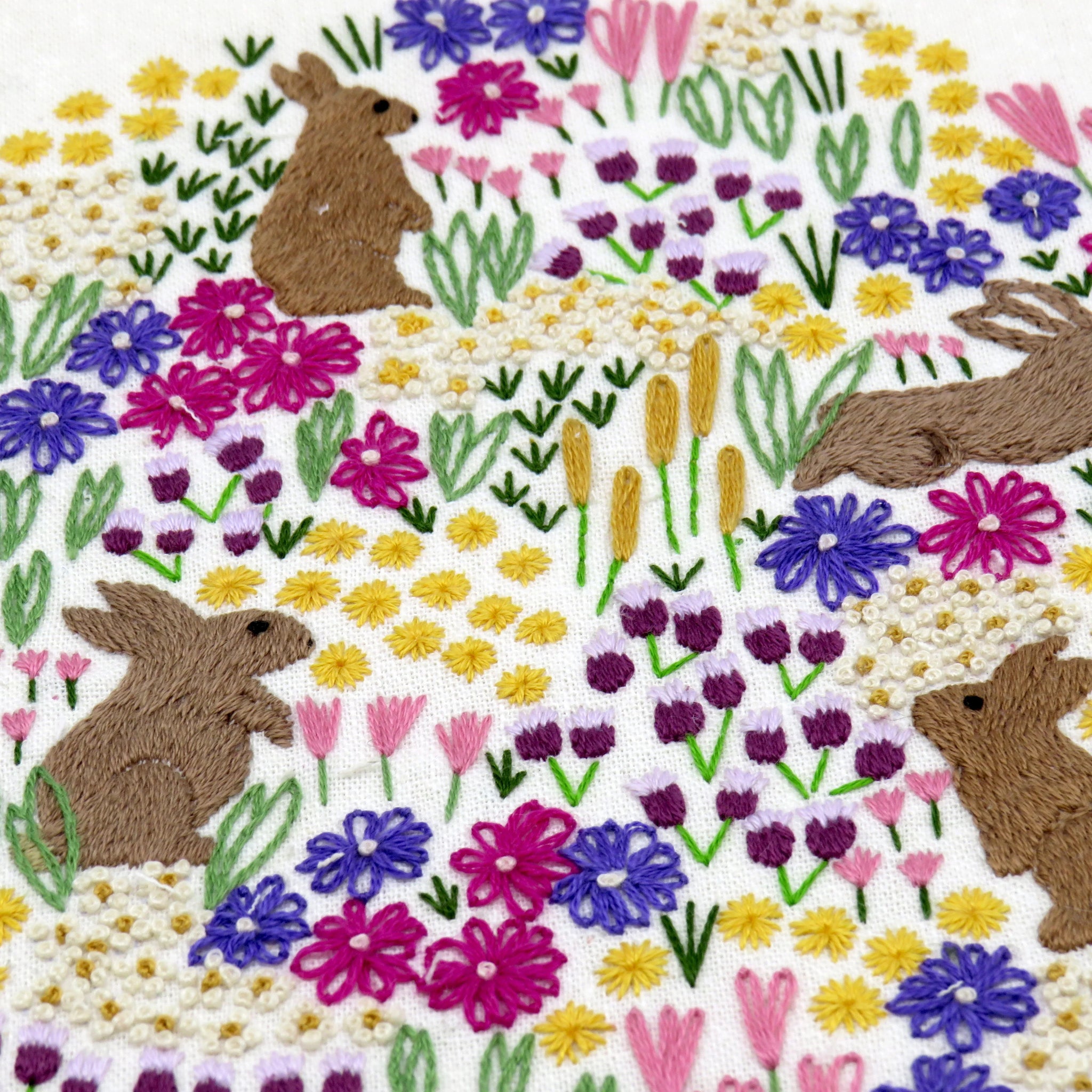Embroidered design of bunnies and flowers on a white background
