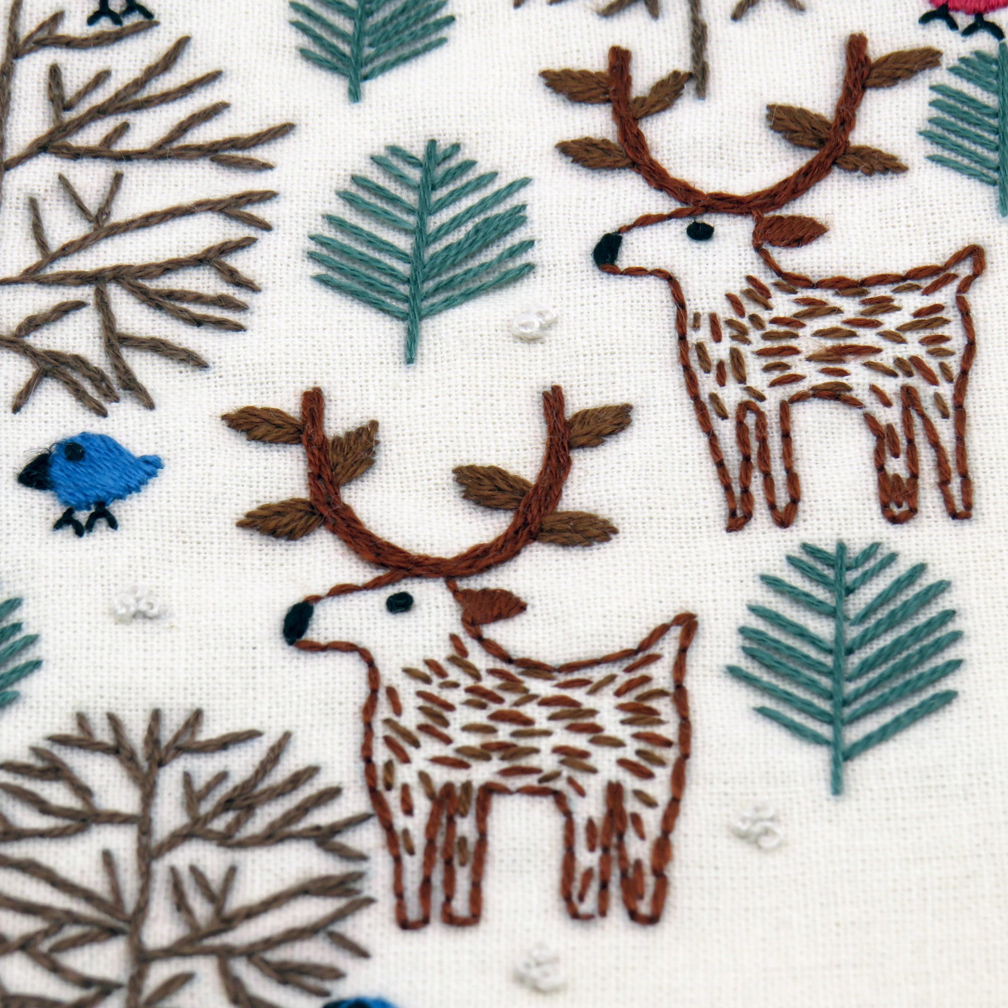 Embroidered pattern of deer and foliage on fabric