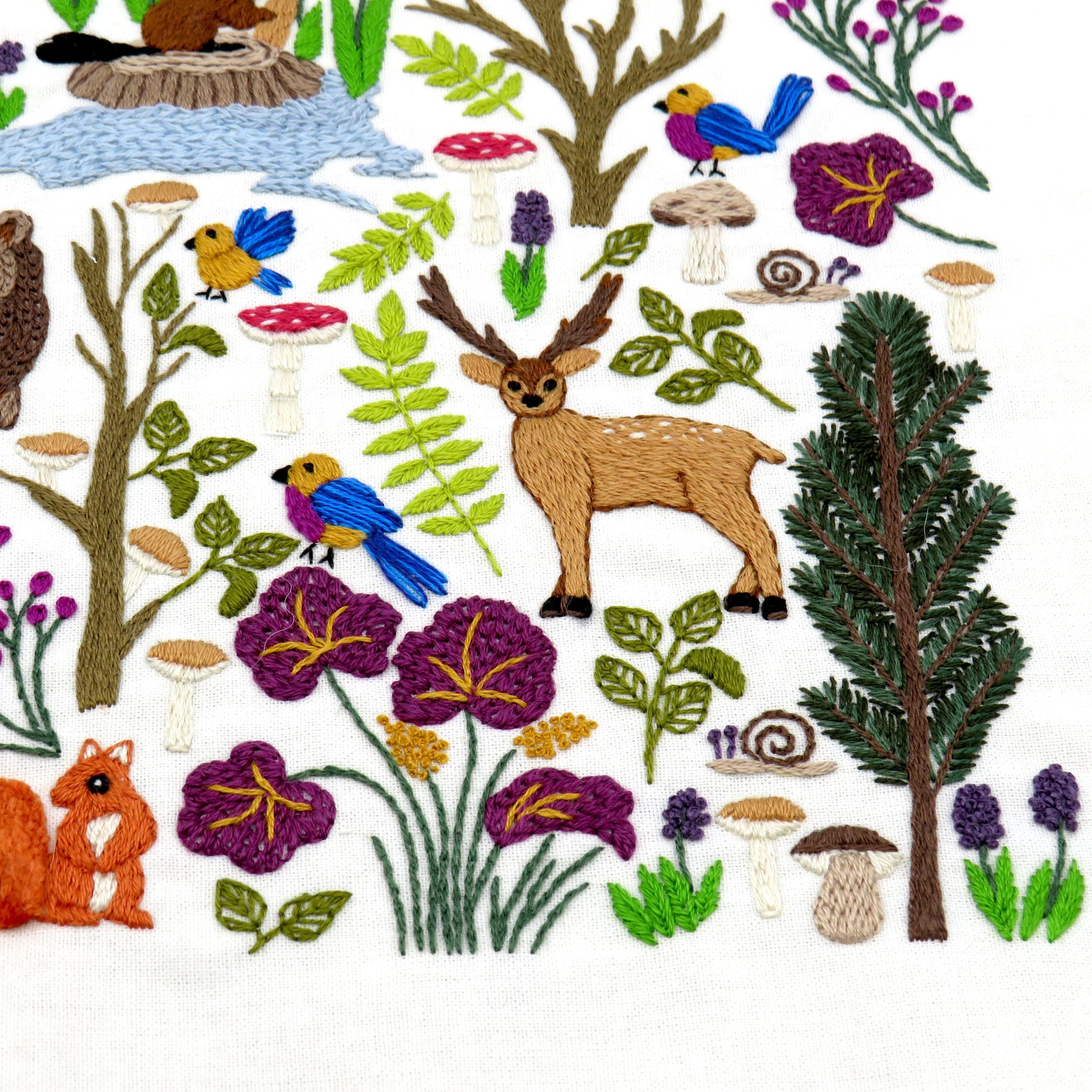 Collection of embroidered forest elements including trees, animals, and flowers on a white background.