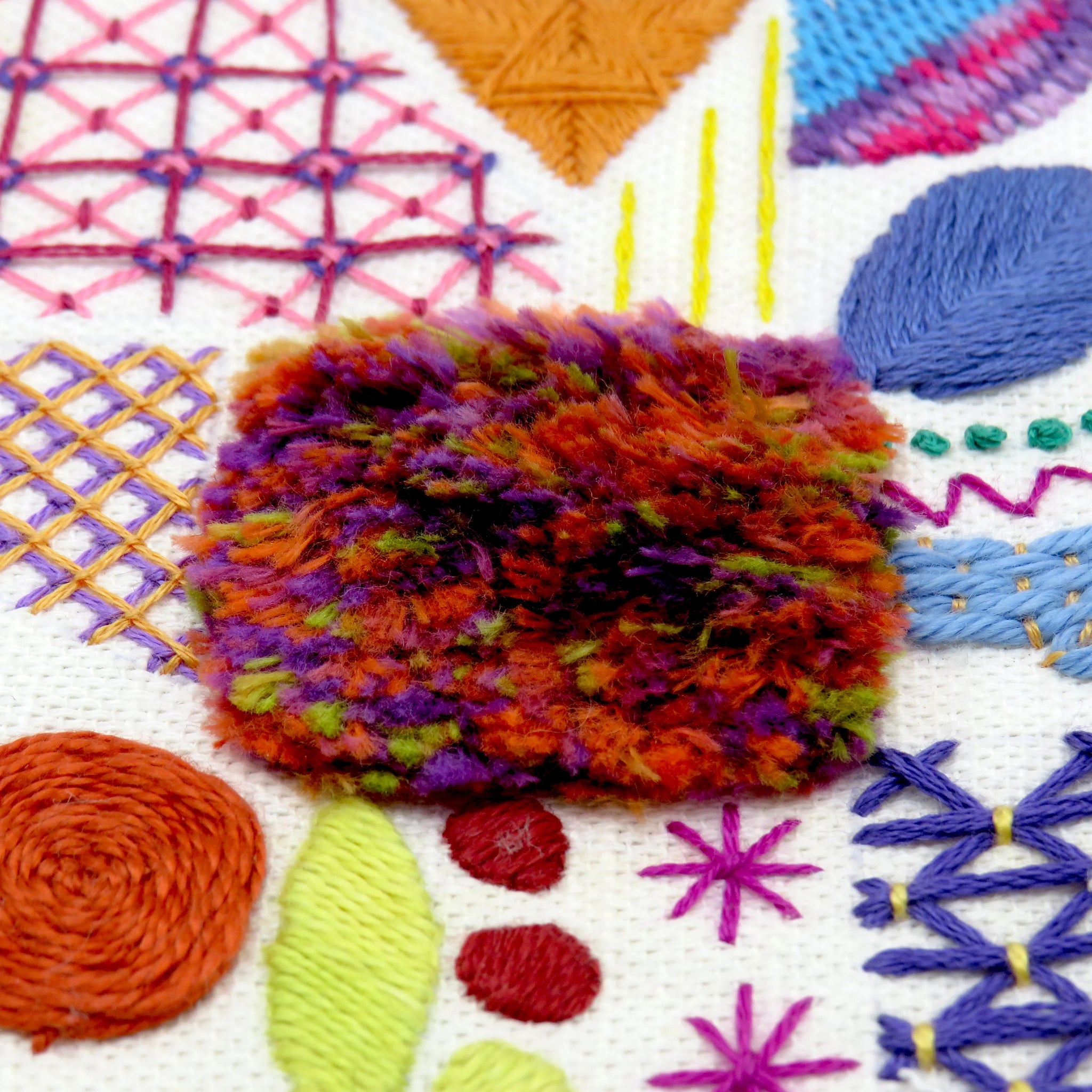 Colorful textured fabric swatch on a background of embroidered patterns