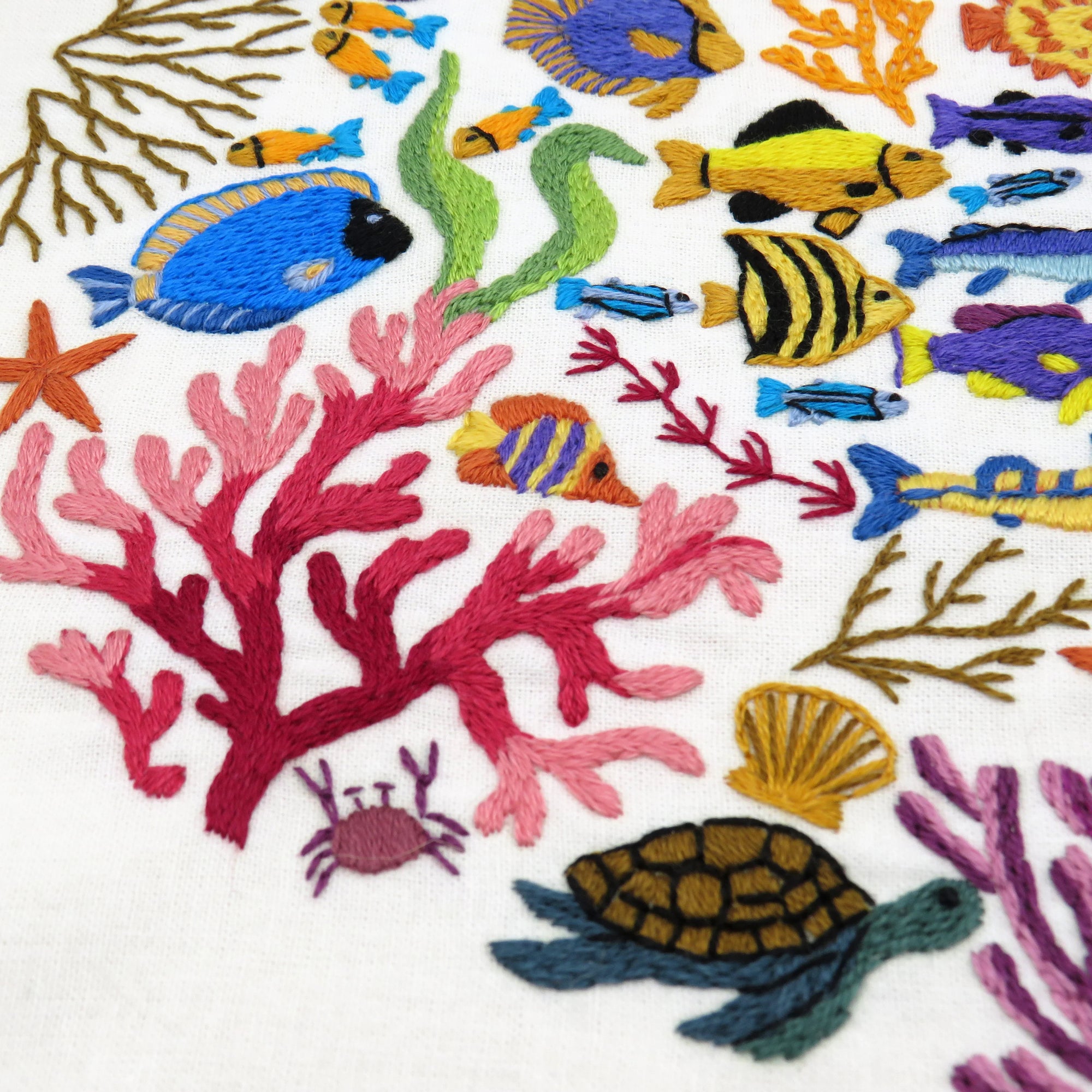 Embroidered design of colorful fish, coral, and sea creatures on a white background
