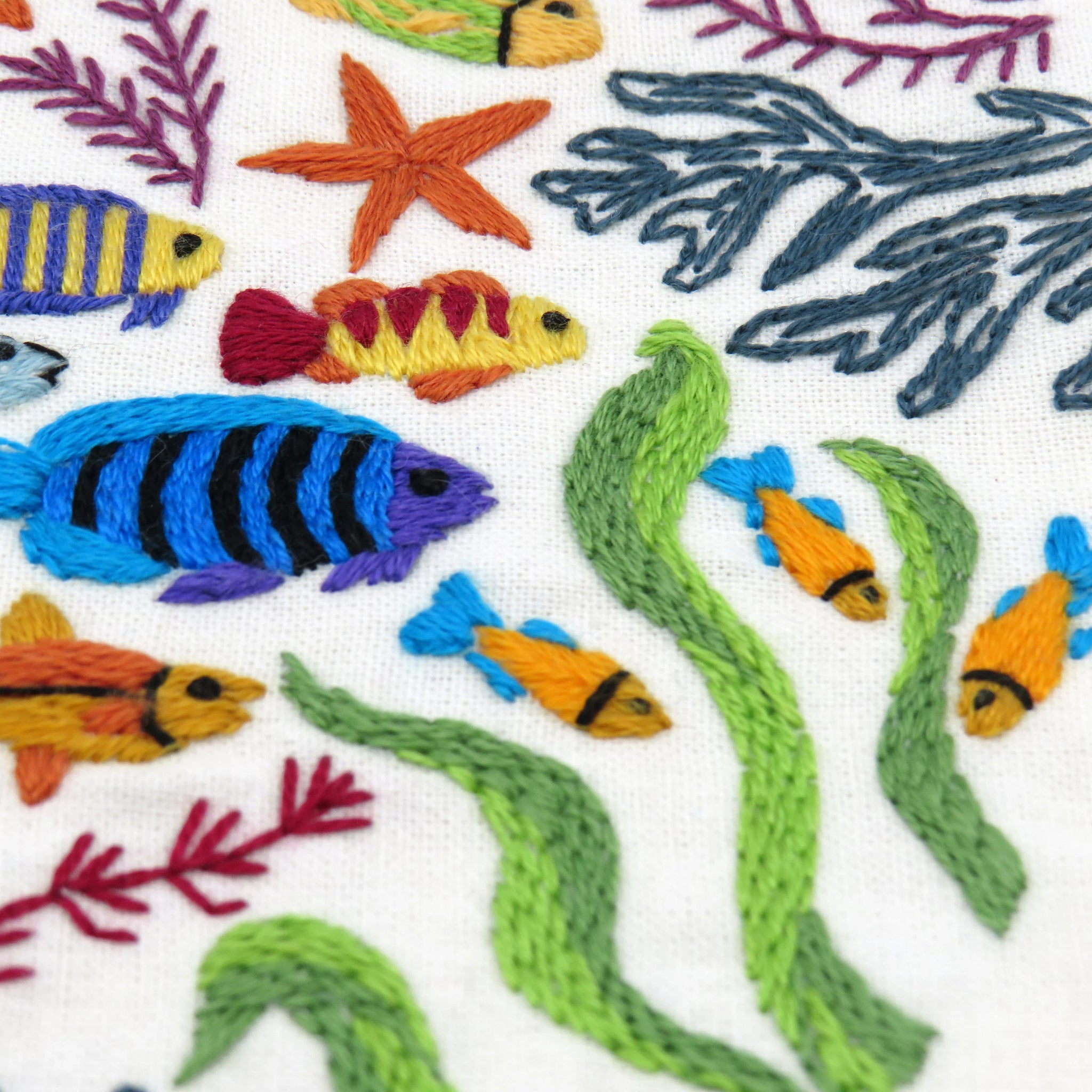 Embroidered pattern of colorful fish and seaweed on a white background