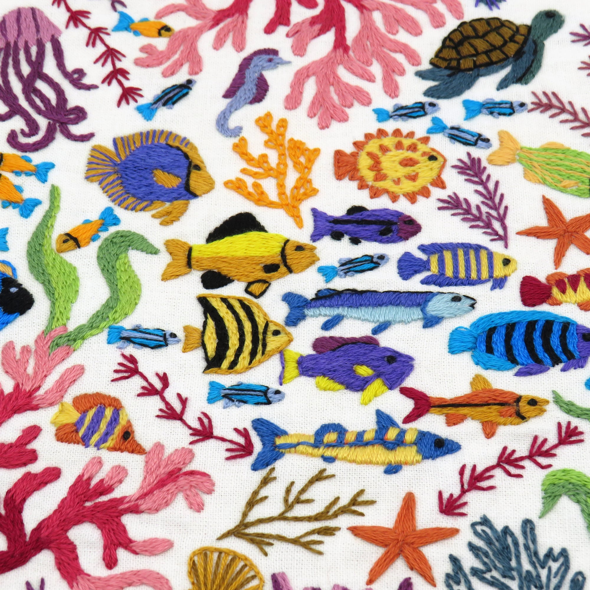 Colorful embroidered pattern of sea creatures and plants on a white background