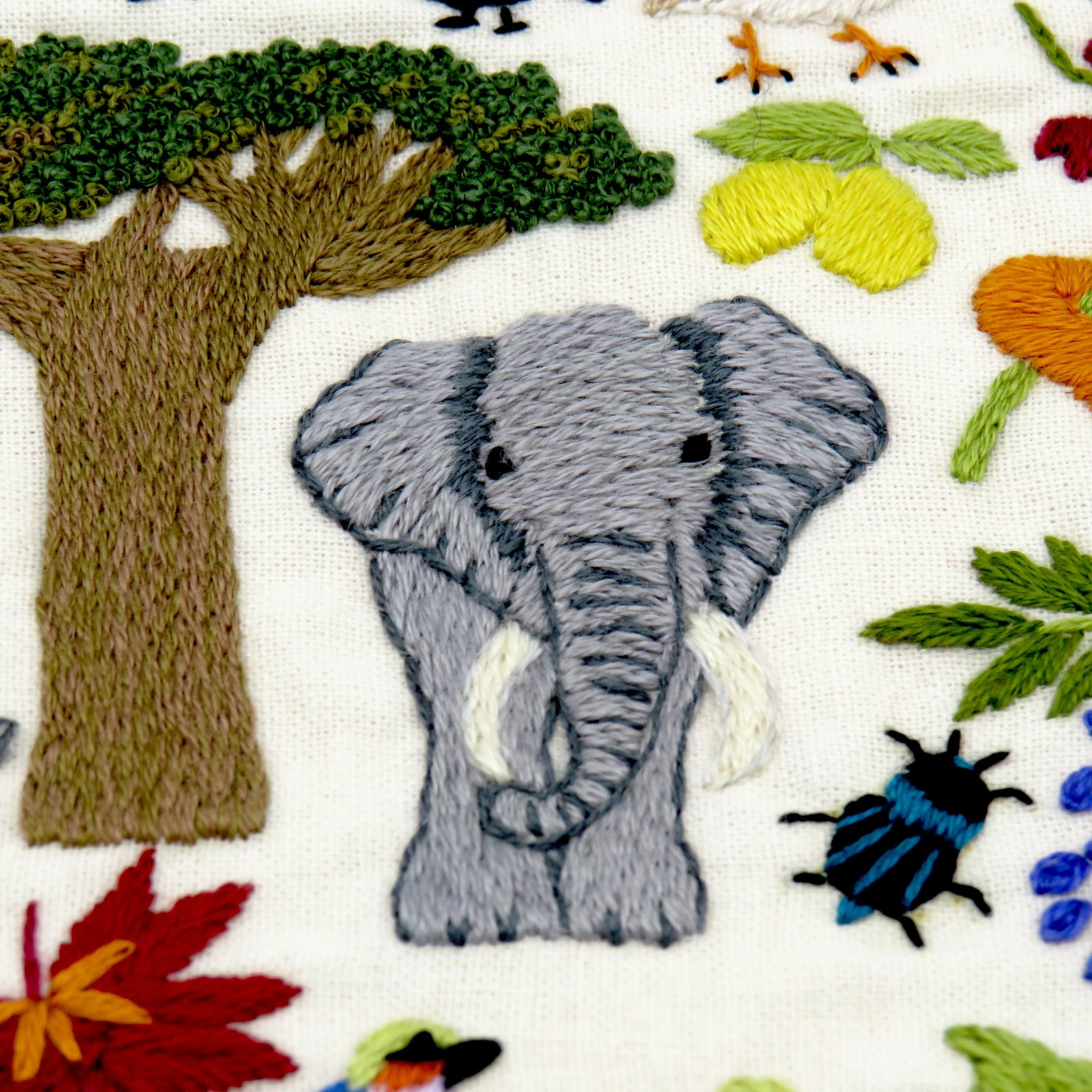 Embroidered pattern with animals, trees, and flowers on a white background