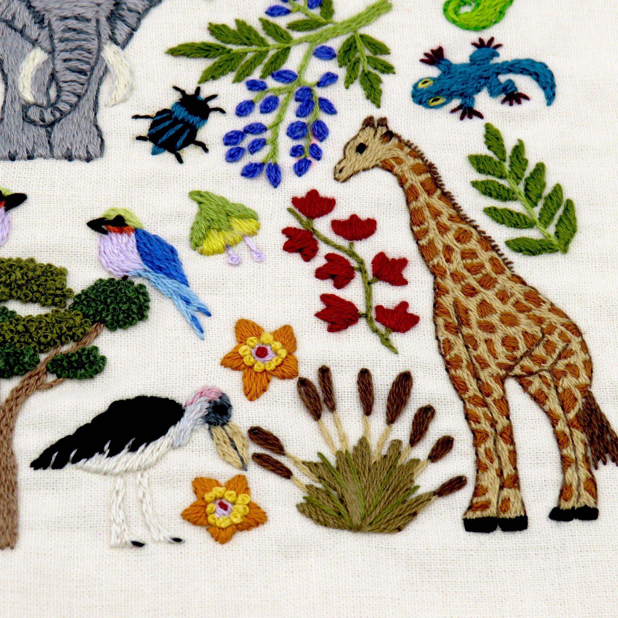 Embroidered pattern with animals, trees, and flowers on a white background