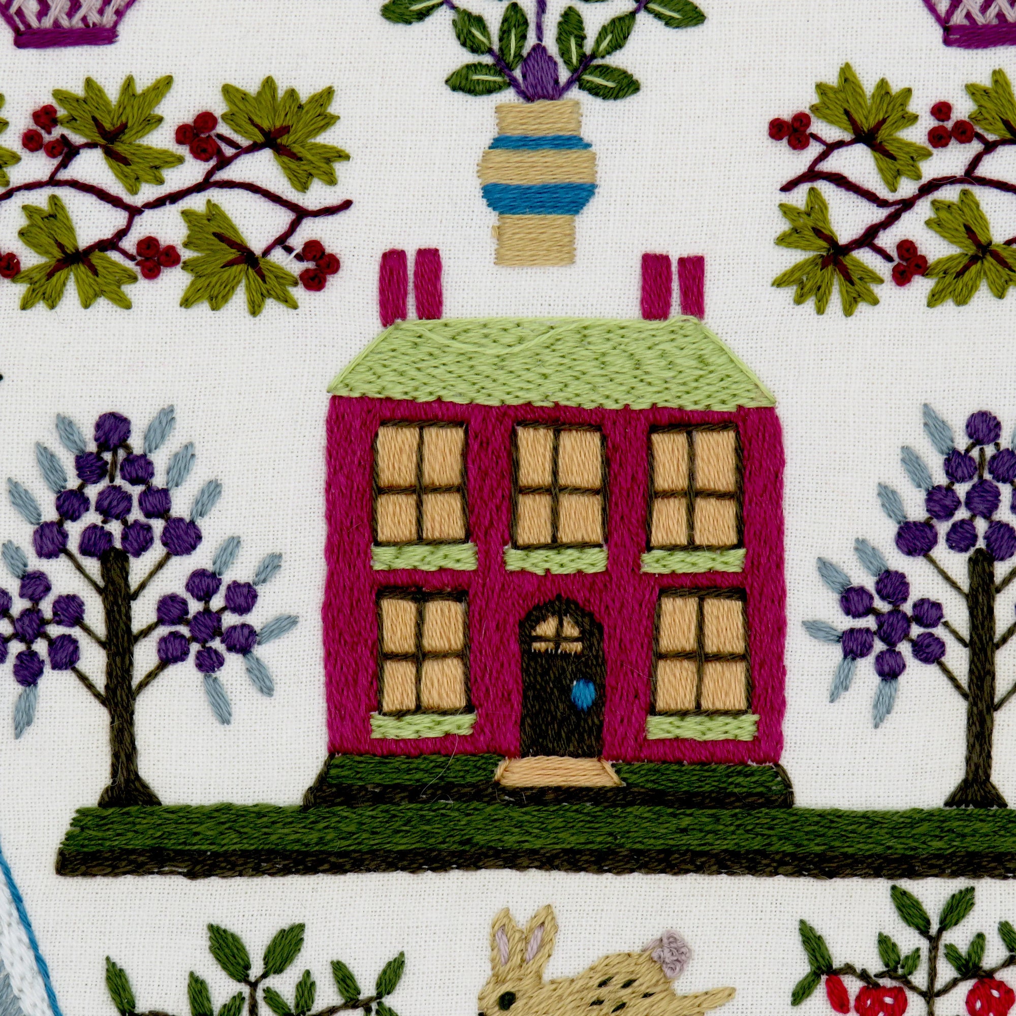 Embroidered house with trees and a rabbit on fabric