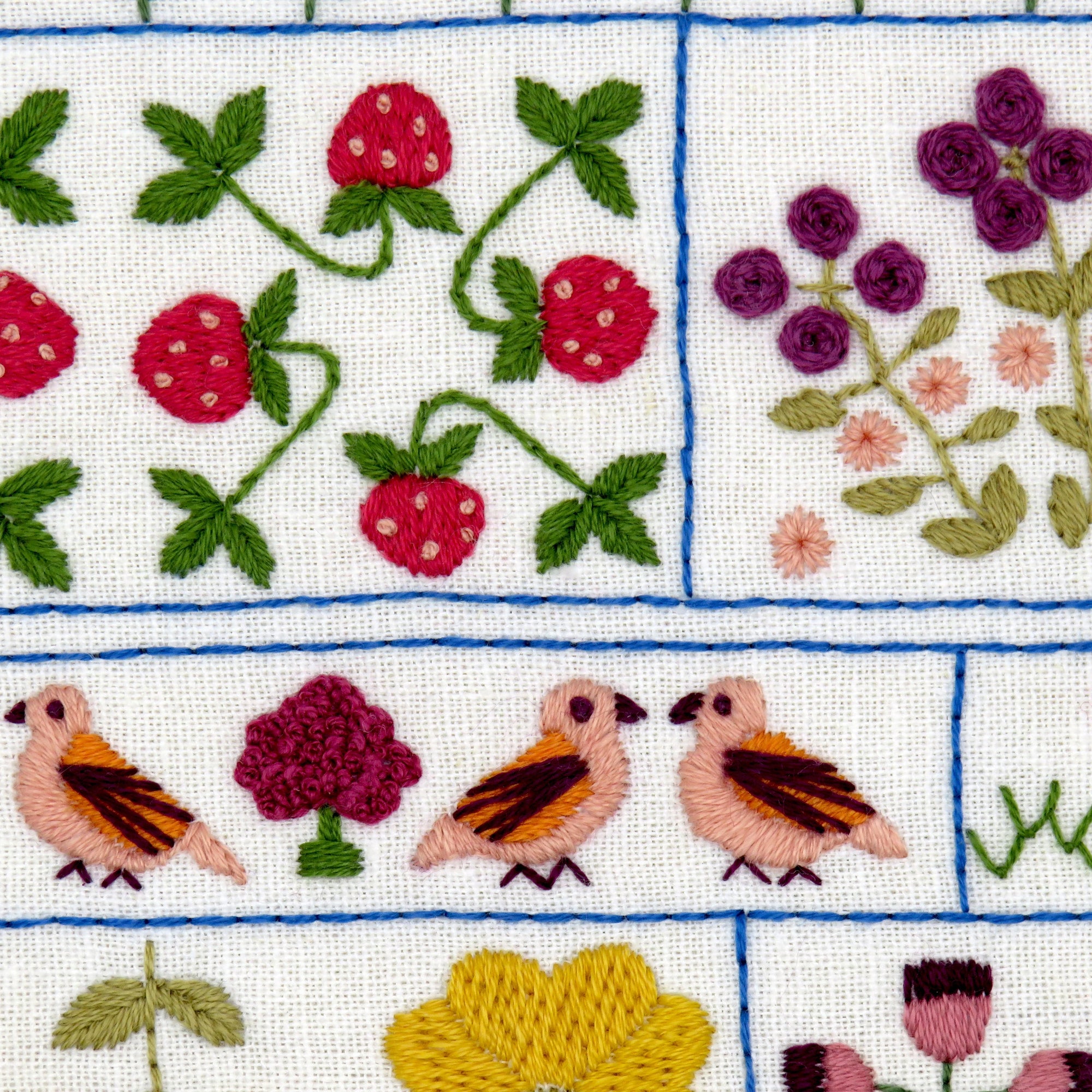 Embroidered design with flowers, birds, and leaves on a grid background