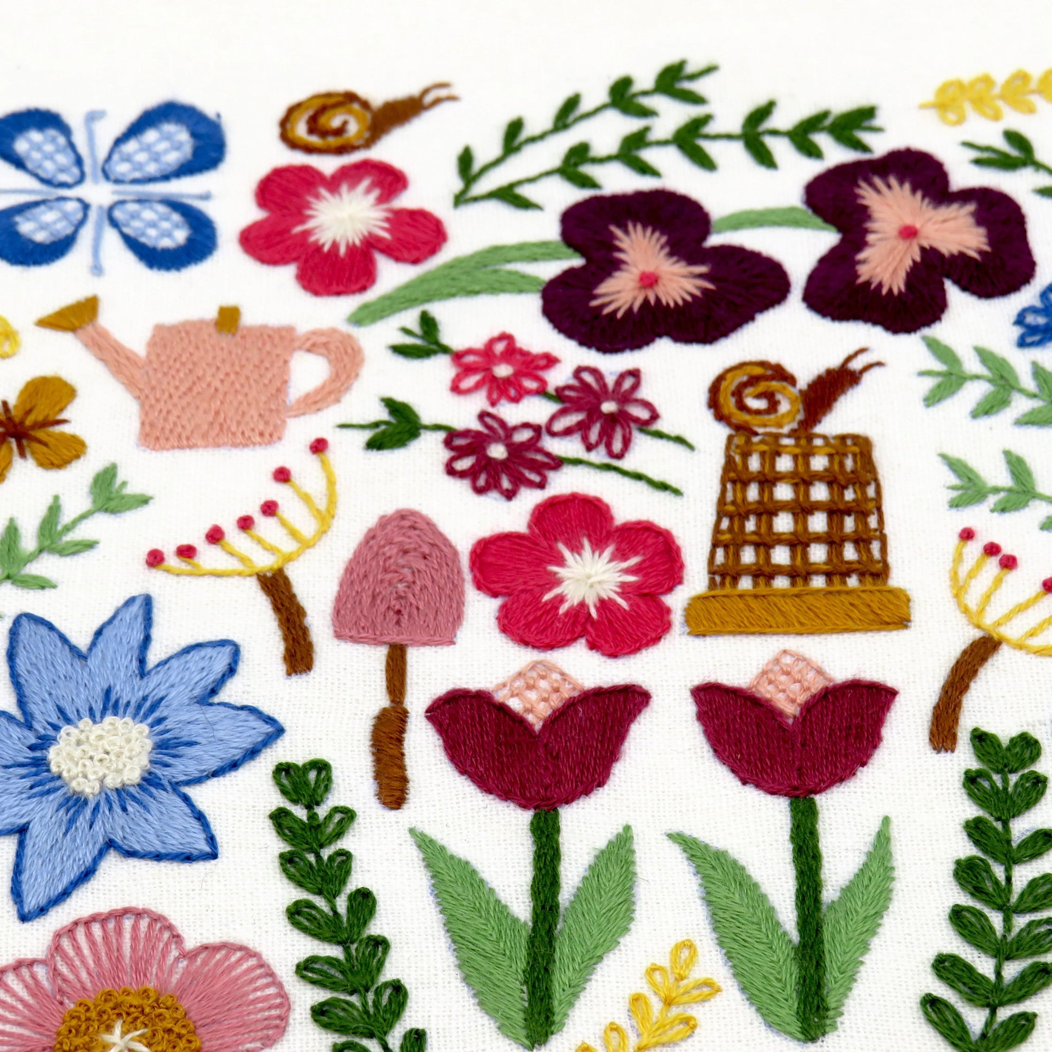 Colorful embroidered pattern of flowers, leaves, and garden elements on a white background